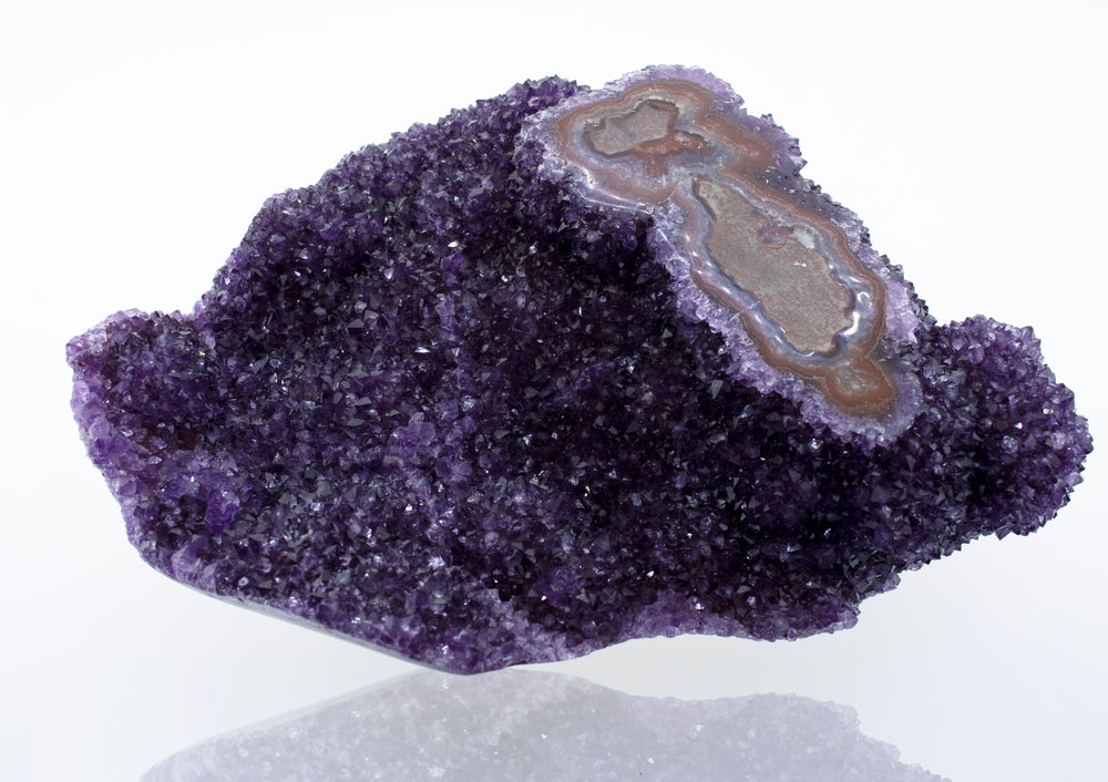 A beautiful Freeform Amethyst Geode decor featuring a purple amethyst crystal on a white surface.