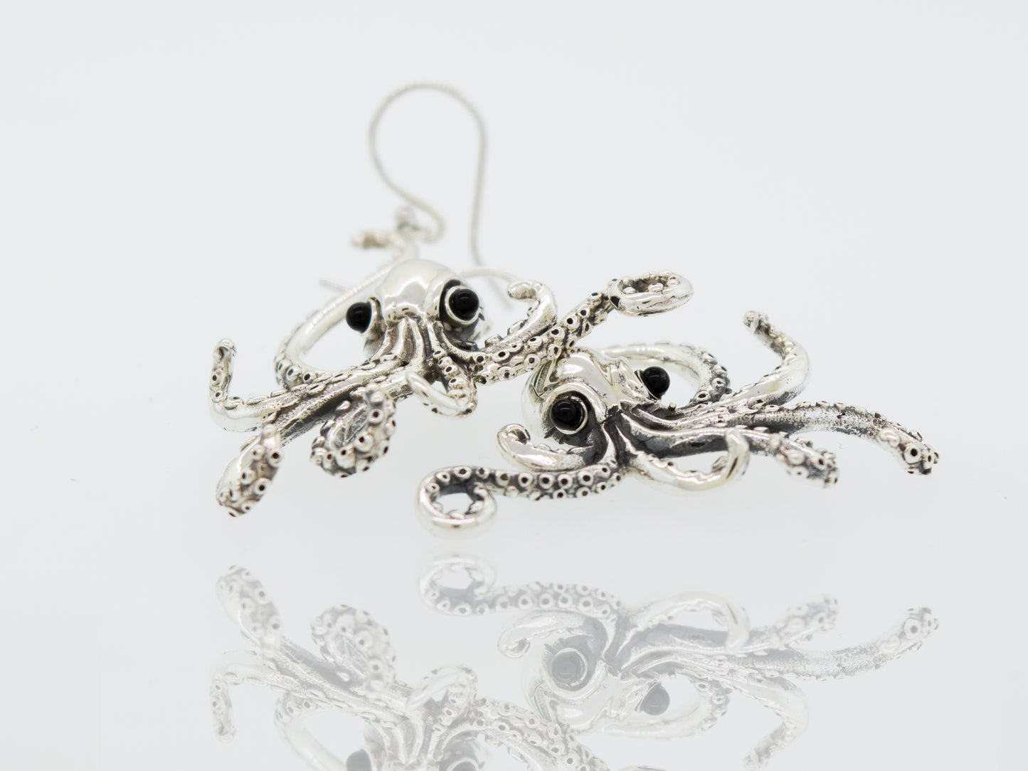 
                  
                    A Super Silver pair of Designer Octopus Earring with Onyx Eyes on a white surface.
                  
                