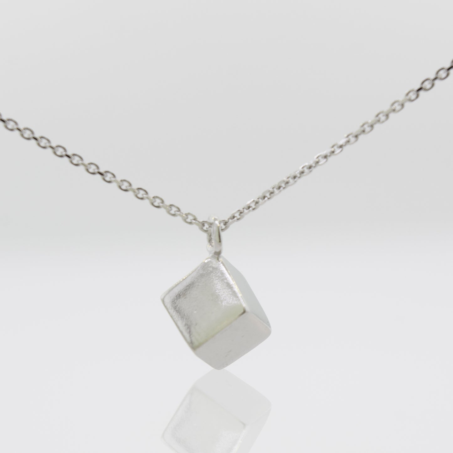 A Super Silver Sleek Three Dimensional Silver Cube Necklace with a cube pendant.