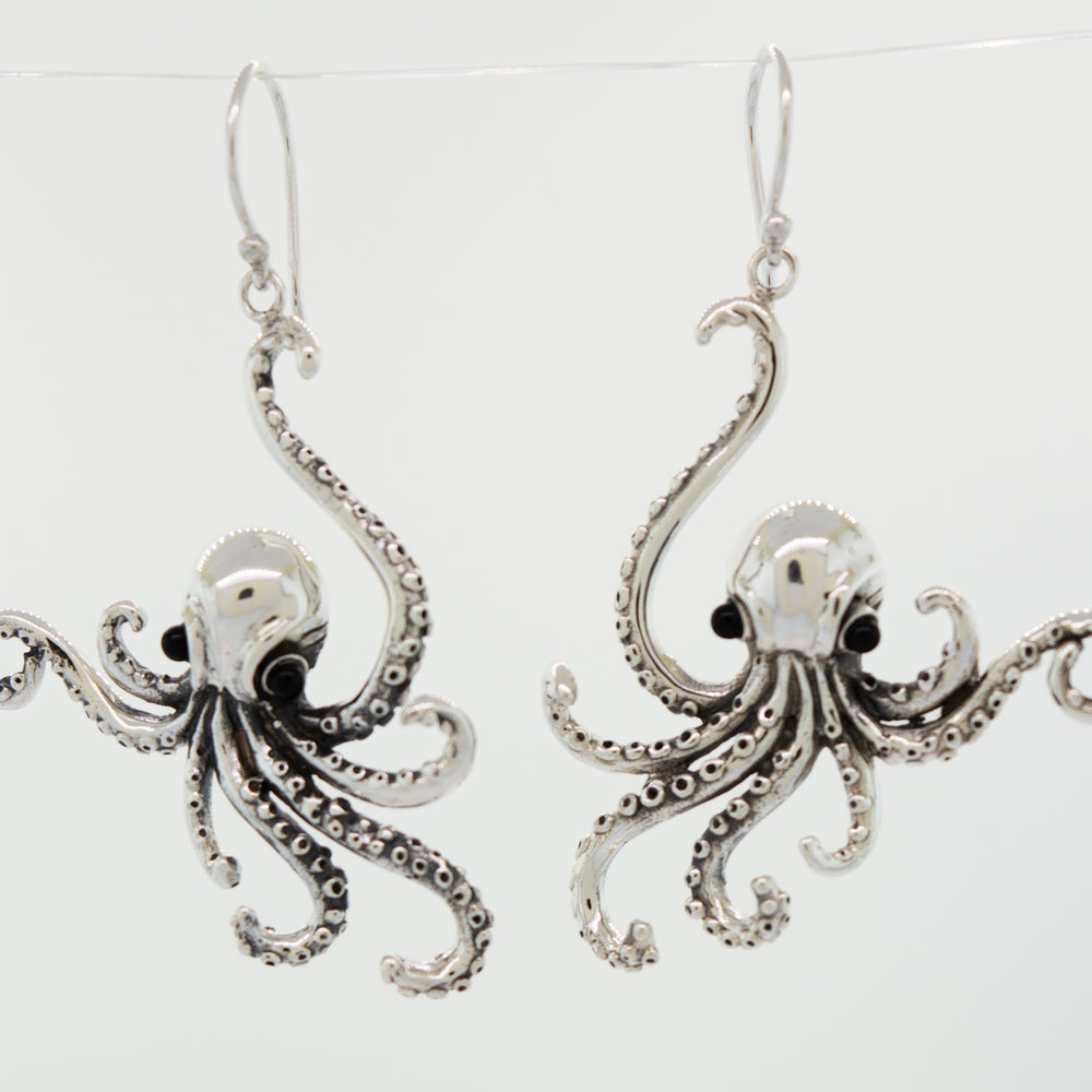 
                  
                    A pair of Super Silver Designer Octopus Earring with Onyx Eyes, delicately hanging from a wire.
                  
                