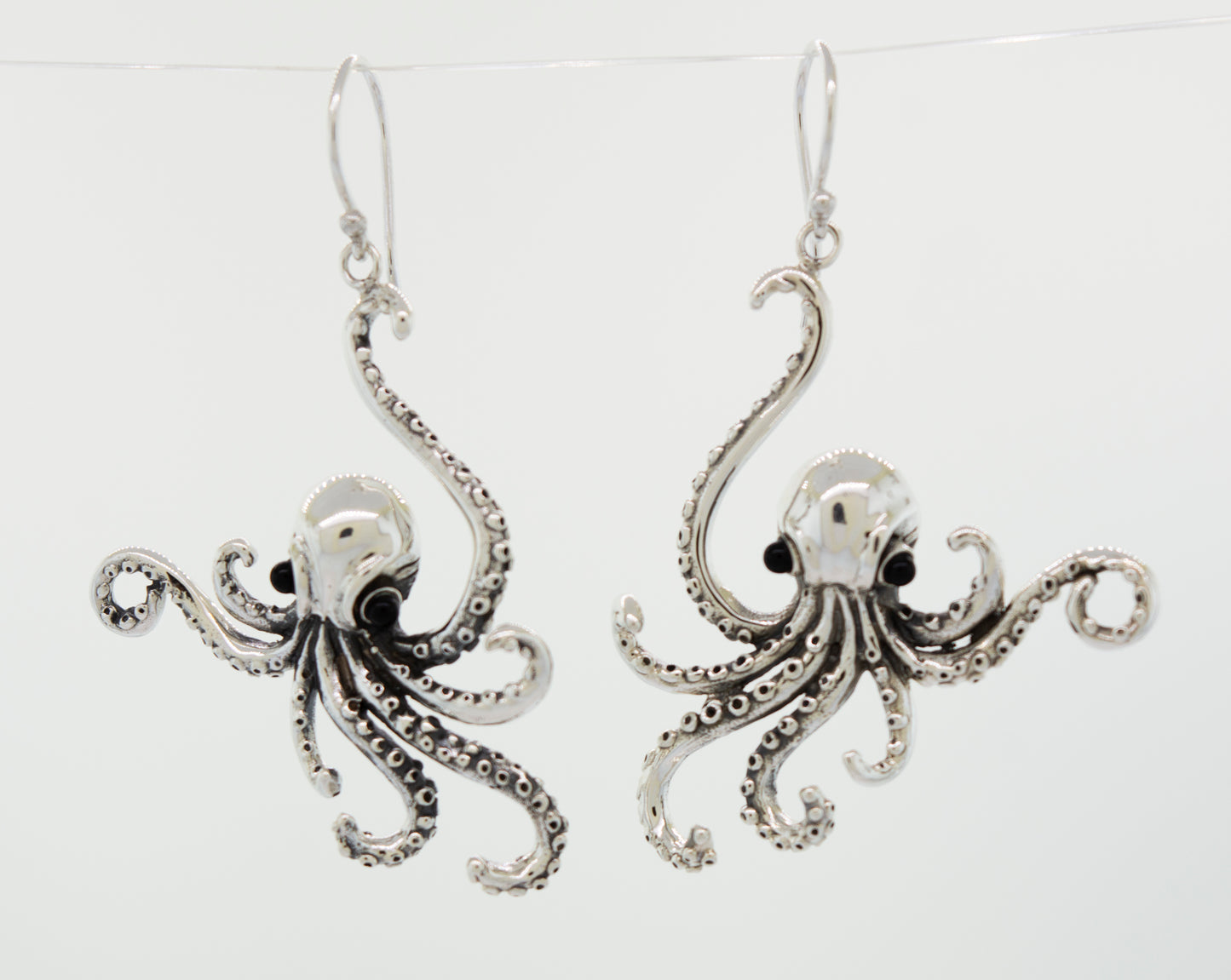 
                  
                    A pair of Super Silver Designer Octopus Earring with Onyx Eyes, delicately hanging from a wire.
                  
                