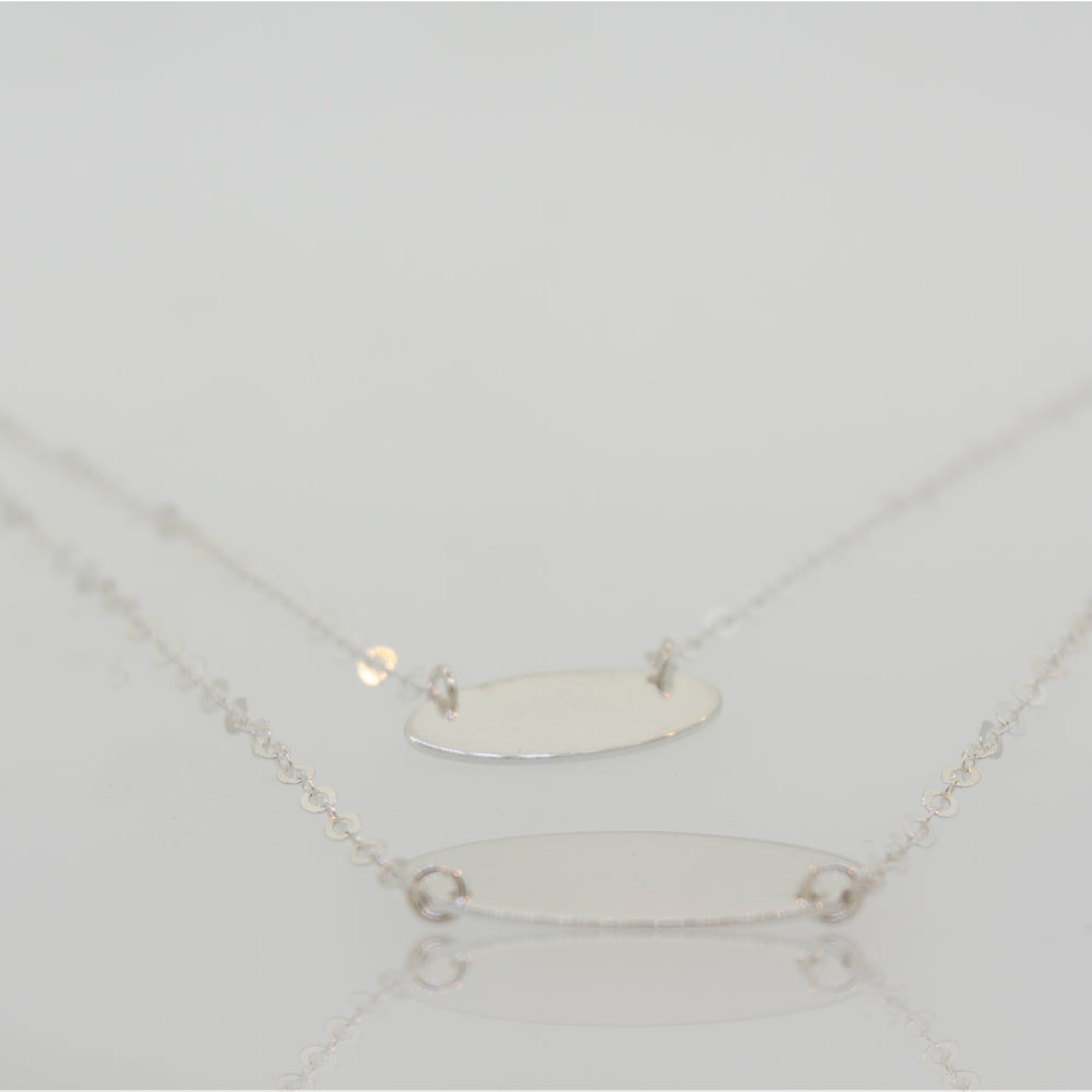 
                  
                    Two Elegant Sterling Silver Necklaces with Oval Disc Pendants by Super Silver on a white surface.
                  
                