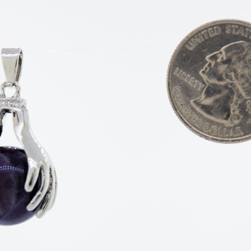 
                  
                    A Sphere Crystal Pendant adorned with Super Silver hands, placed next to a dime.
                  
                