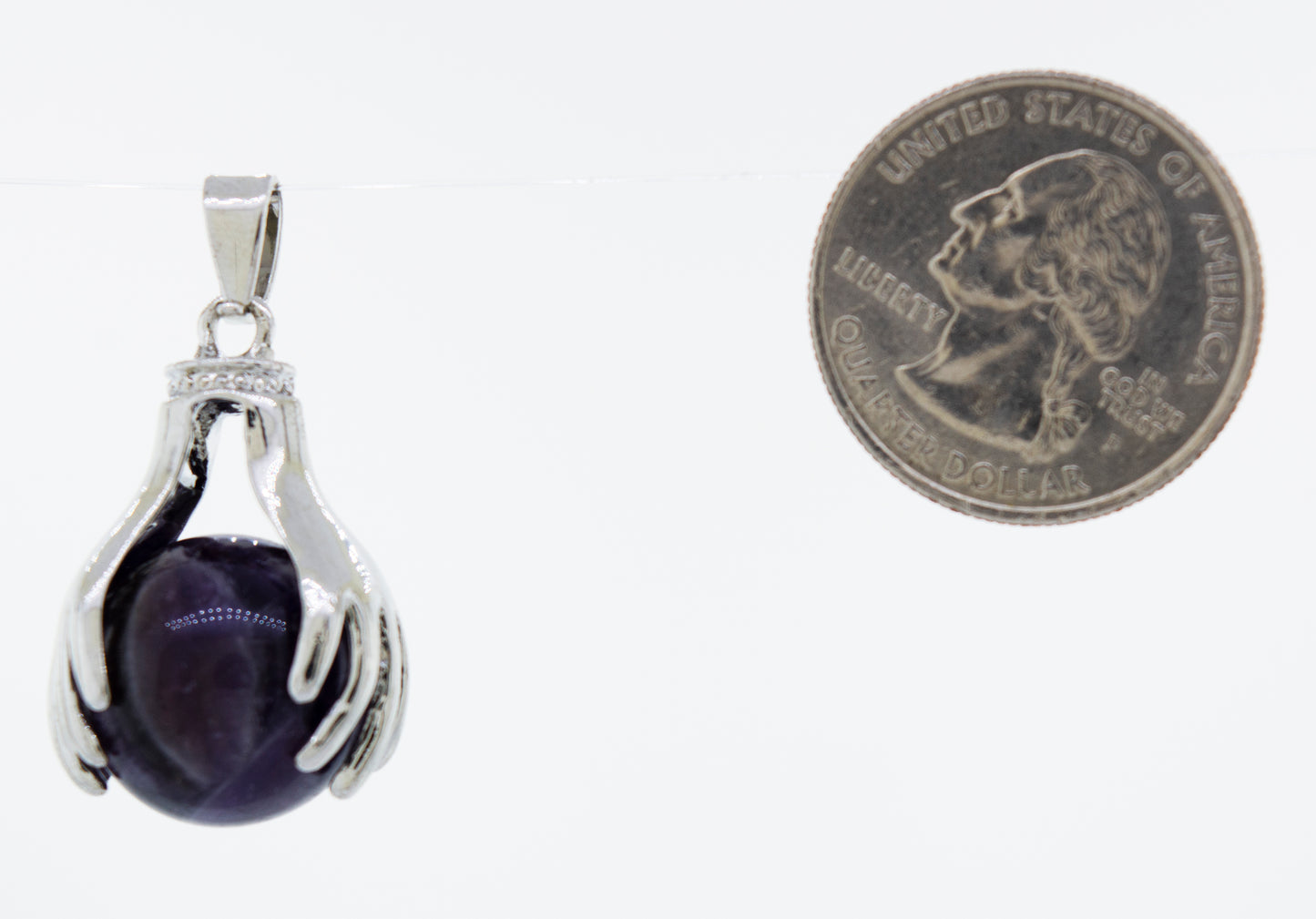 
                  
                    A Sphere Crystal Pendant adorned with Super Silver hands, placed next to a dime.
                  
                