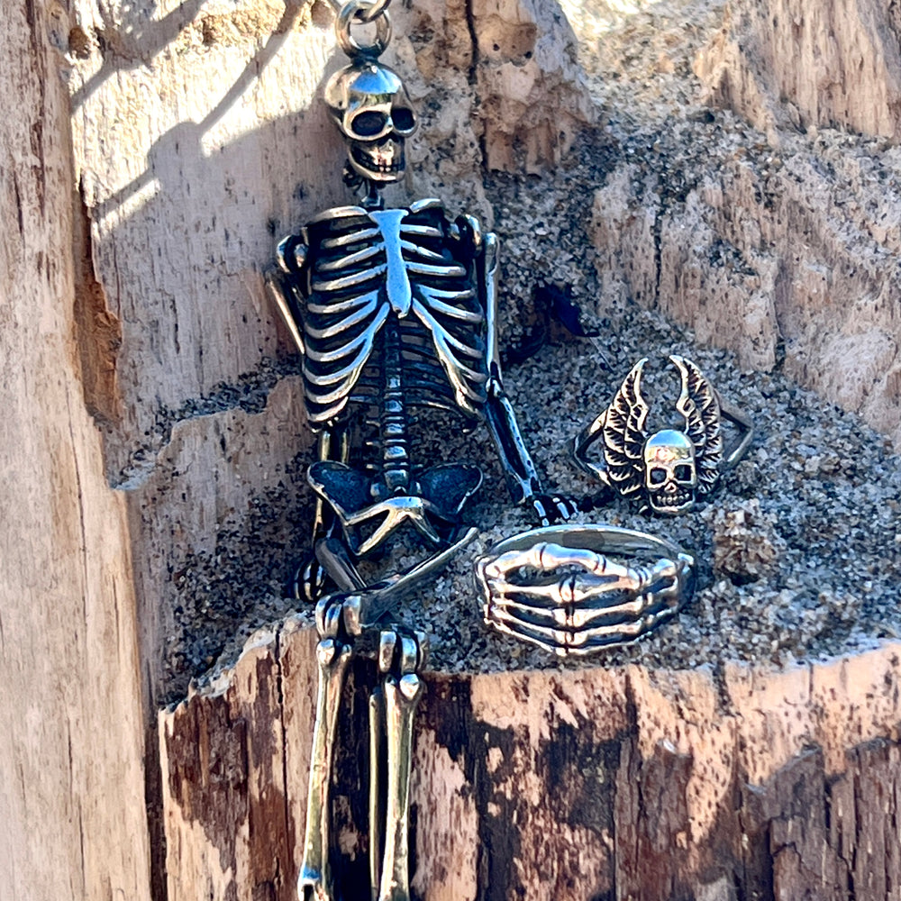 A Super Silver Large Skeleton Pendant sits on a statement piece of wood, showcasing its unique style.