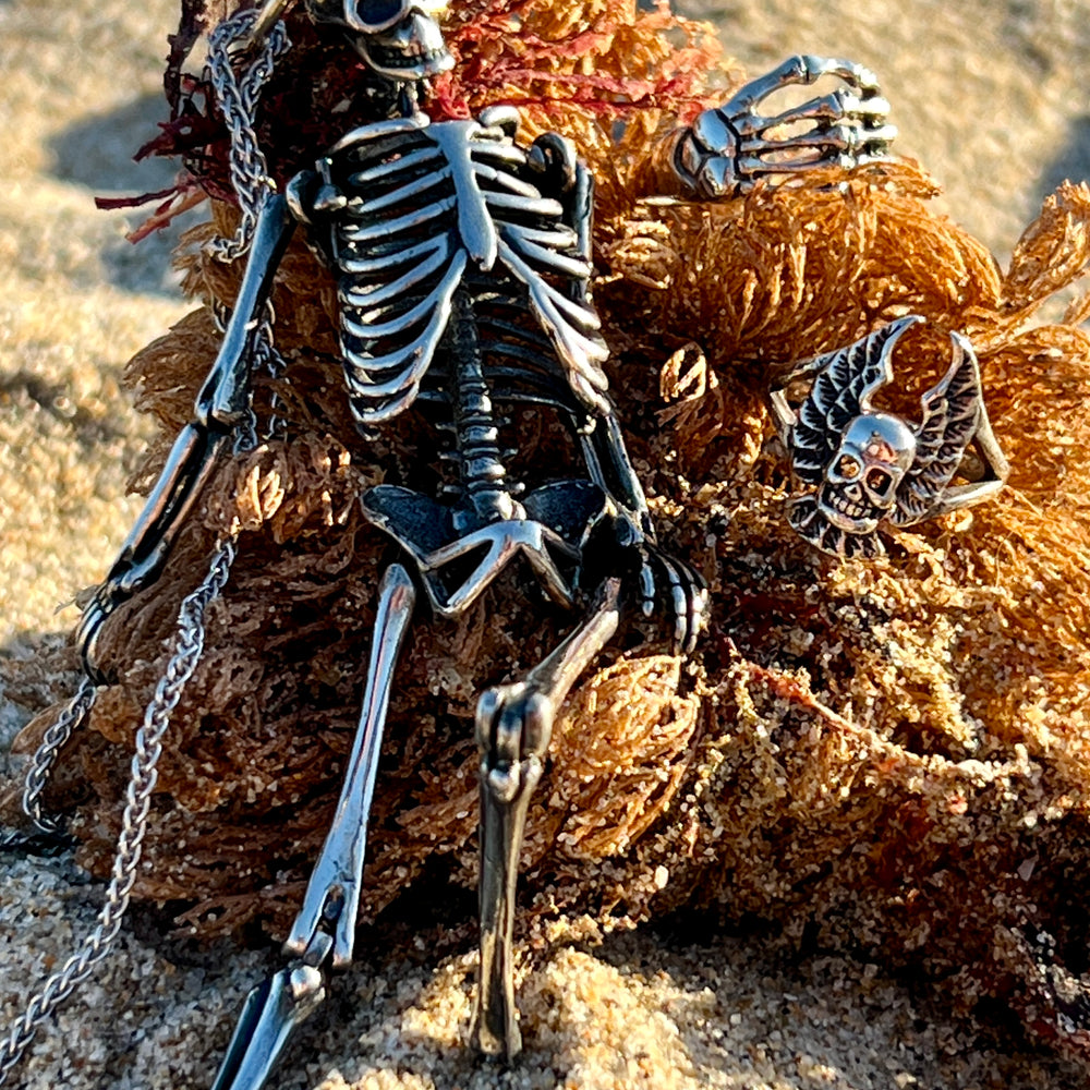 A statement piece, a Super Silver Large Skeleton Pendant, stylishly perched on a rock in the sand.
