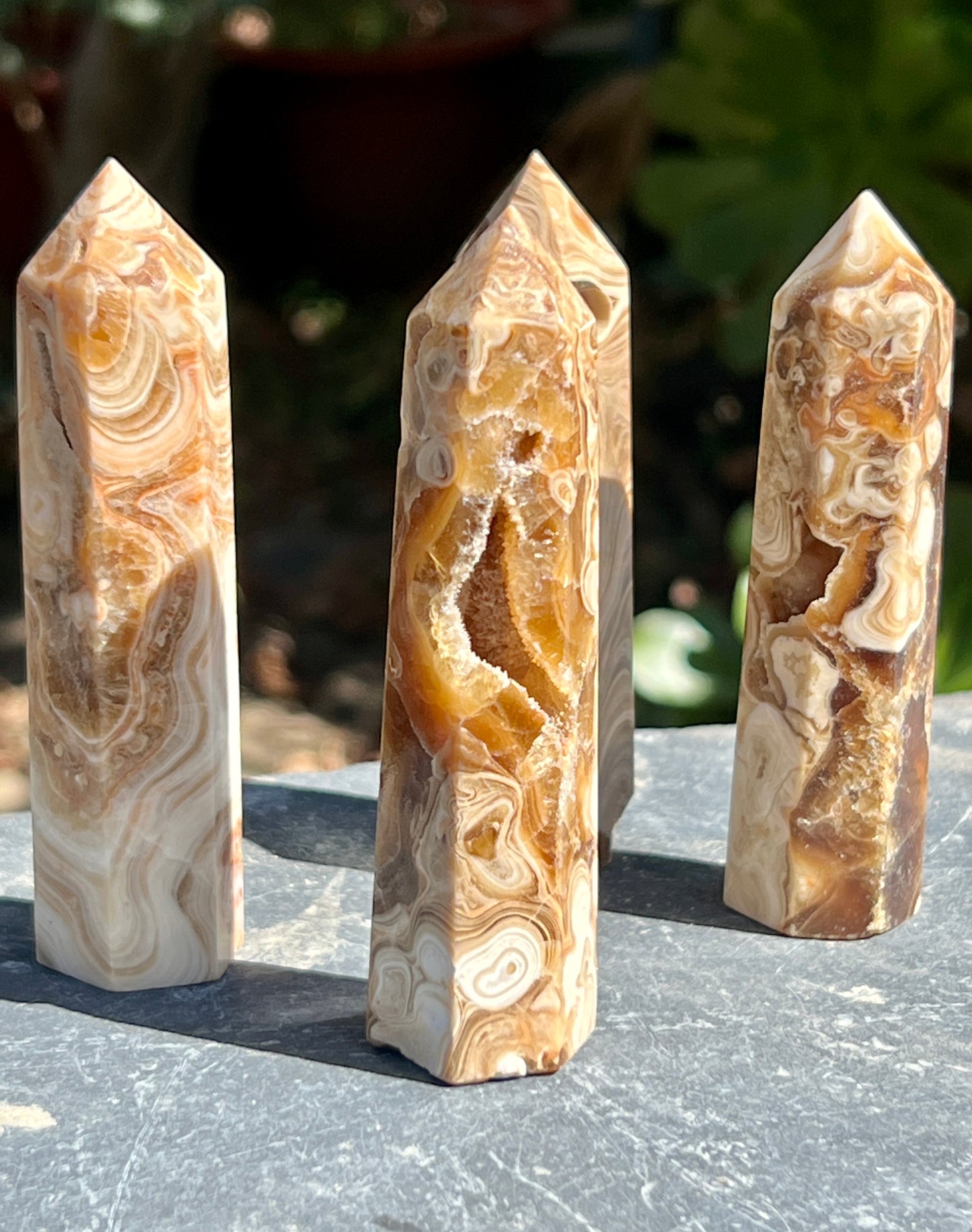 Three pieces of brown aragonite obelisk sitting on top of a table, serving as decorative obelisks.