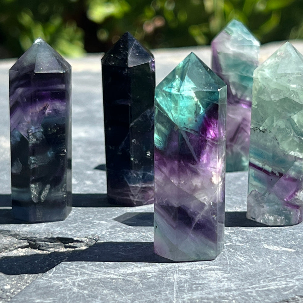 
                  
                    A Rainbow Fluorite Obelisk on a stone slab, perfect for decor enthusiasts seeking a touch of green or purple in their space.
                  
                
