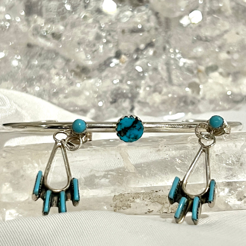 
                  
                    A pair of Delicate Needlepoint Zuni Turquoise Earrings by Super Silver with turquoise stones on top of a crystal.
                  
                