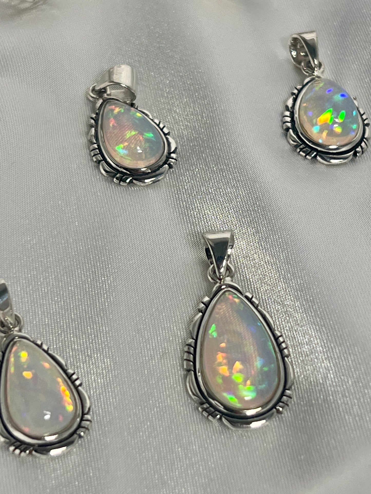 
                  
                    Four Super Silver Ethiopian Opal Teardrop Shaped Pendants with Detailed Setting on a white cloth.
                  
                