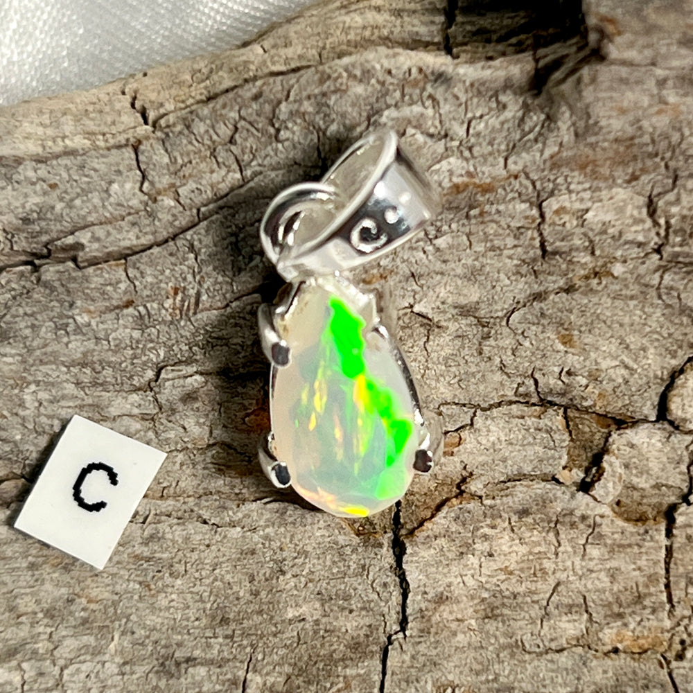 
                  
                    A stunning Dainty Prong Set Facet Cut Teardrop Shaped Ethiopian Opal pendant adorned with the letter "C", crafted in high-quality Sterling Silver, by Super Silver.
                  
                