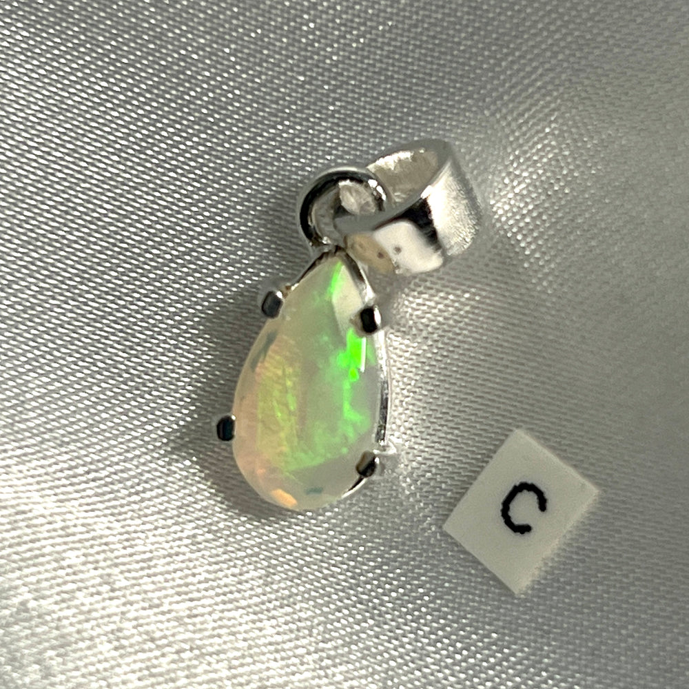 
                  
                    A Super Silver Dainty Prong Set Facet Cut Teardrop Shaped Ethiopian Opal Pendant with the letter c on it.
                  
                