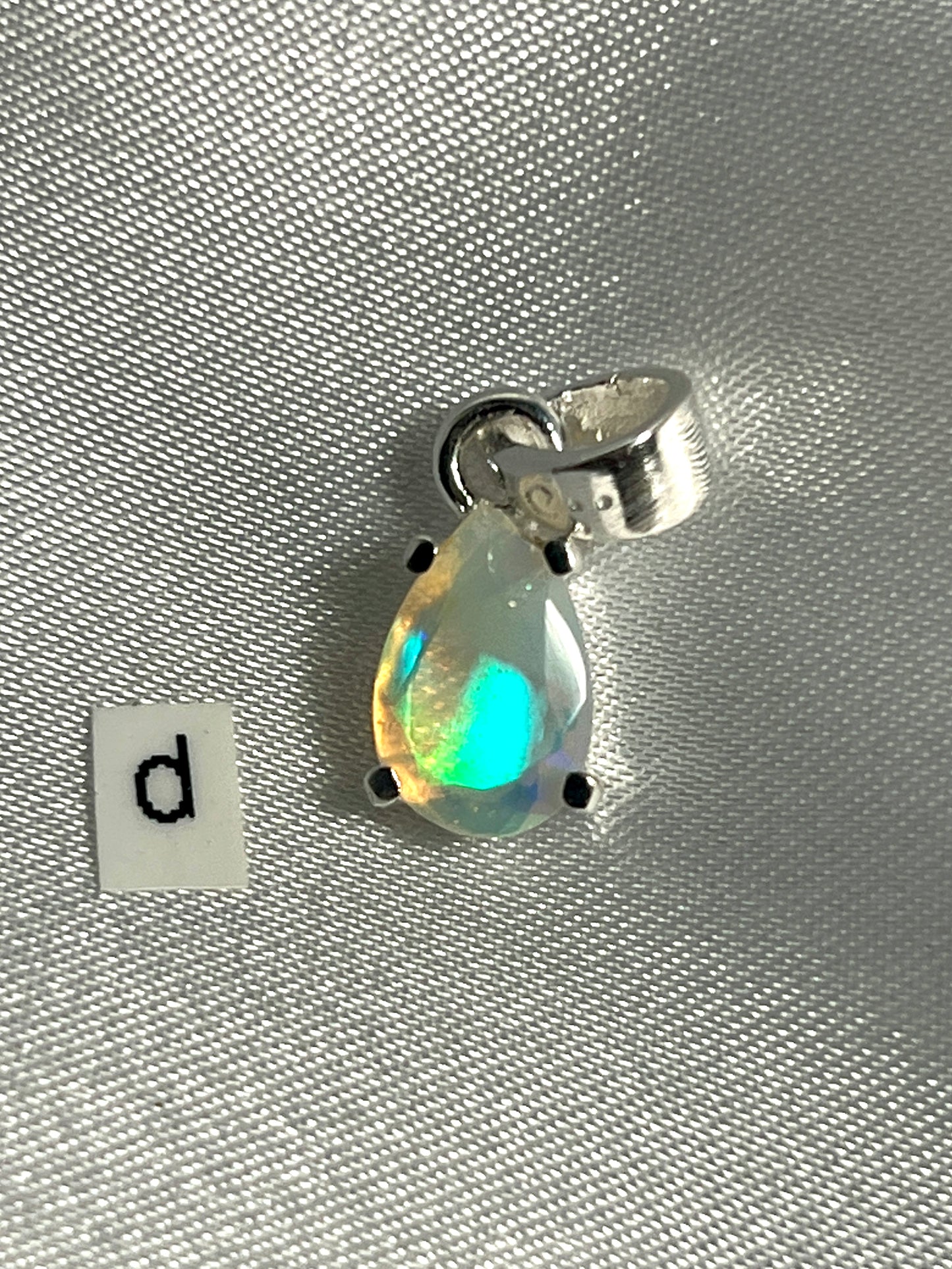 
                  
                    A stunning Dainty Prong Set Facet Cut Teardrop Shaped Ethiopian Opal Pendant with the letter d crafted in Super Silver.
                  
                