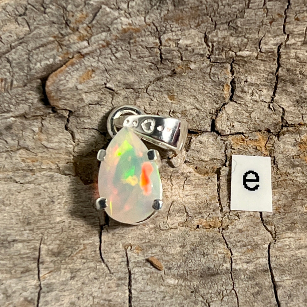 
                  
                    A stunning Dainty Prong Set Facet Cut Teardrop Shaped Ethiopian Opal Pendant with the letter "e" delicately engraved on it, crafted in elegant sterling silver by Super Silver.
                  
                
