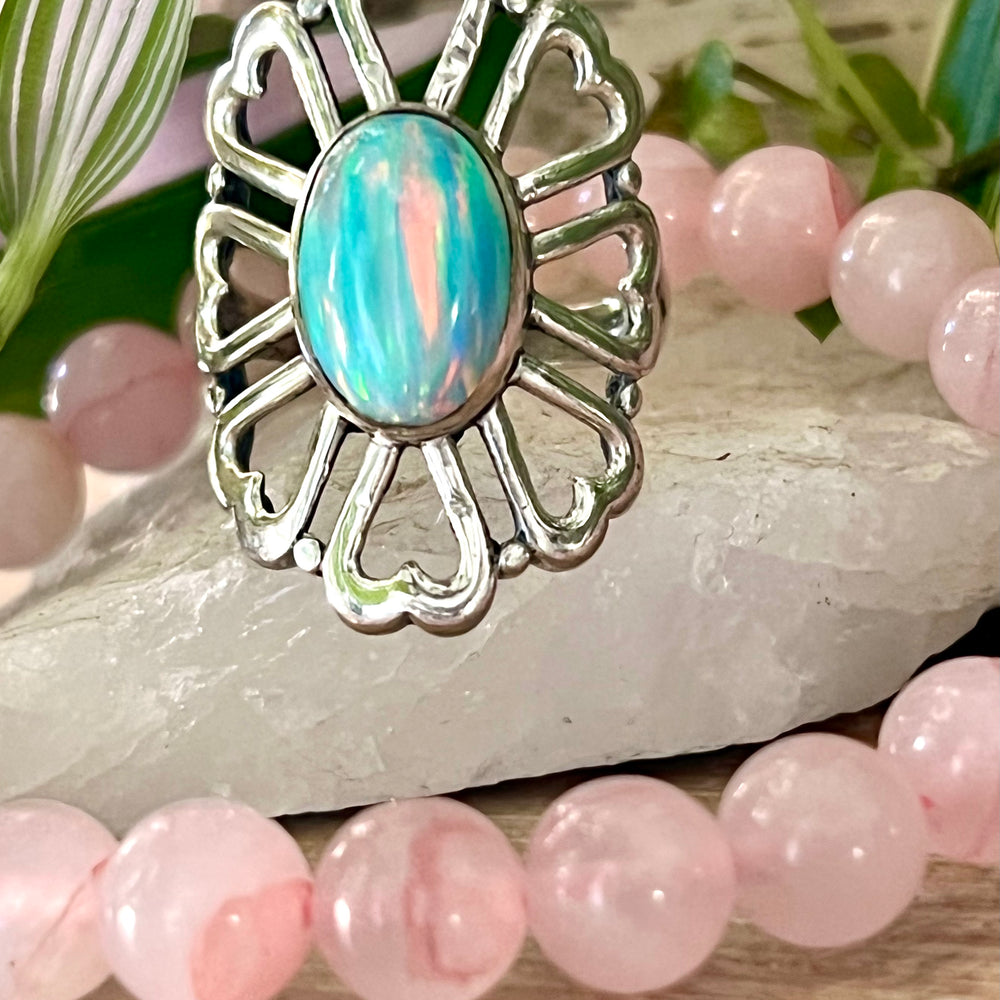 
                  
                    A handcrafted Super Silver American Made Opal Flower Ring with Heart Shaped Petals adorned by pink beads.
                  
                