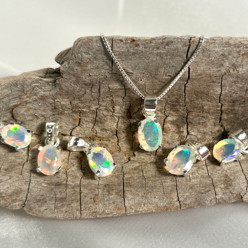 Super Silver's Tiny Facet Cut Prong Set Ethiopian Opal Pendant necklace and earrings on a piece of wood, made with .925 sterling silver.