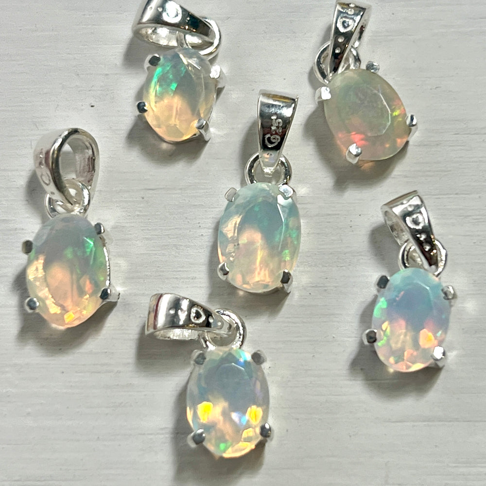 Six Tiny Facet Cut Prong Set Ethiopian Opal Pendants on a dainty, .925 Super Silver surface.