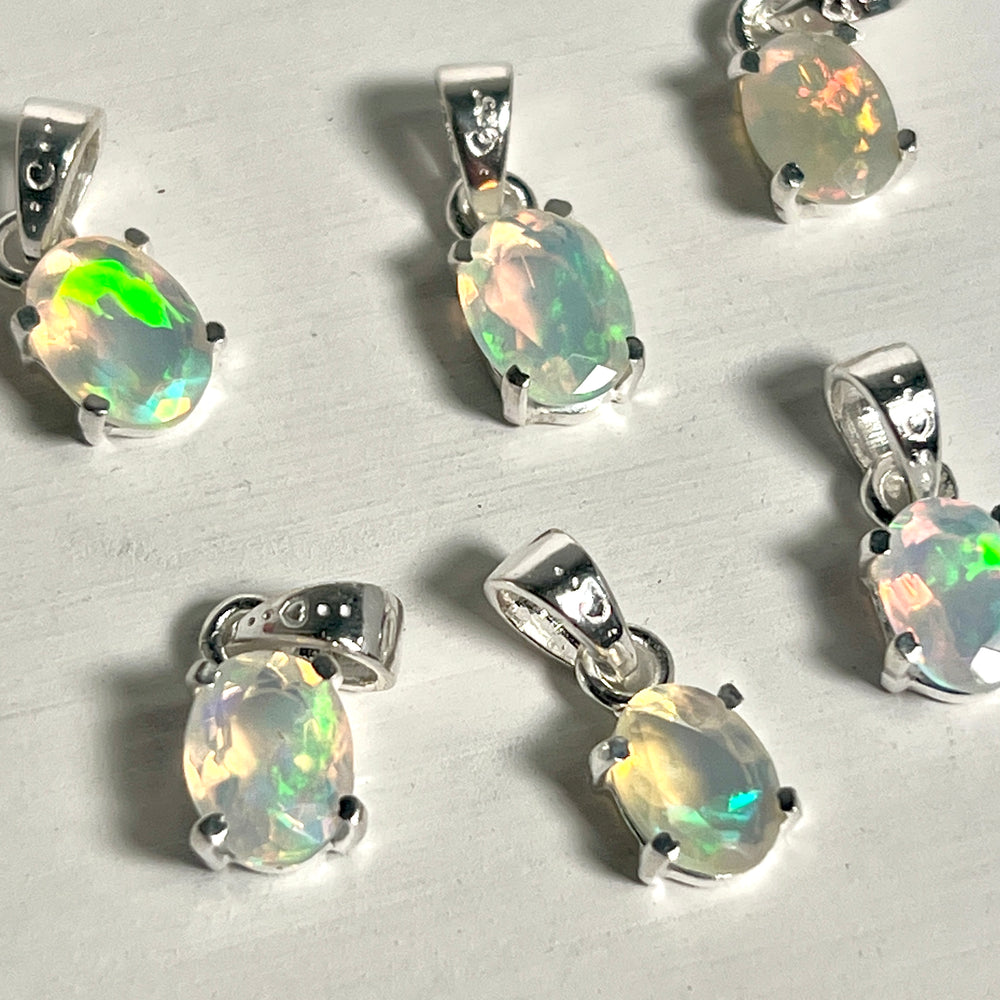 
                  
                    Five Tiny Facet Cut Prong Set Ethiopian Opal Pendants displayed on a white table by Super Silver.
                  
                