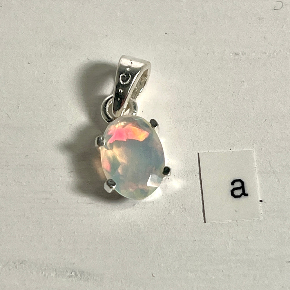 
                  
                    A tiny facet cut prong set Ethiopian Opal pendant with the letter a next to it, crafted in .925 sterling silver by Super Silver.
                  
                