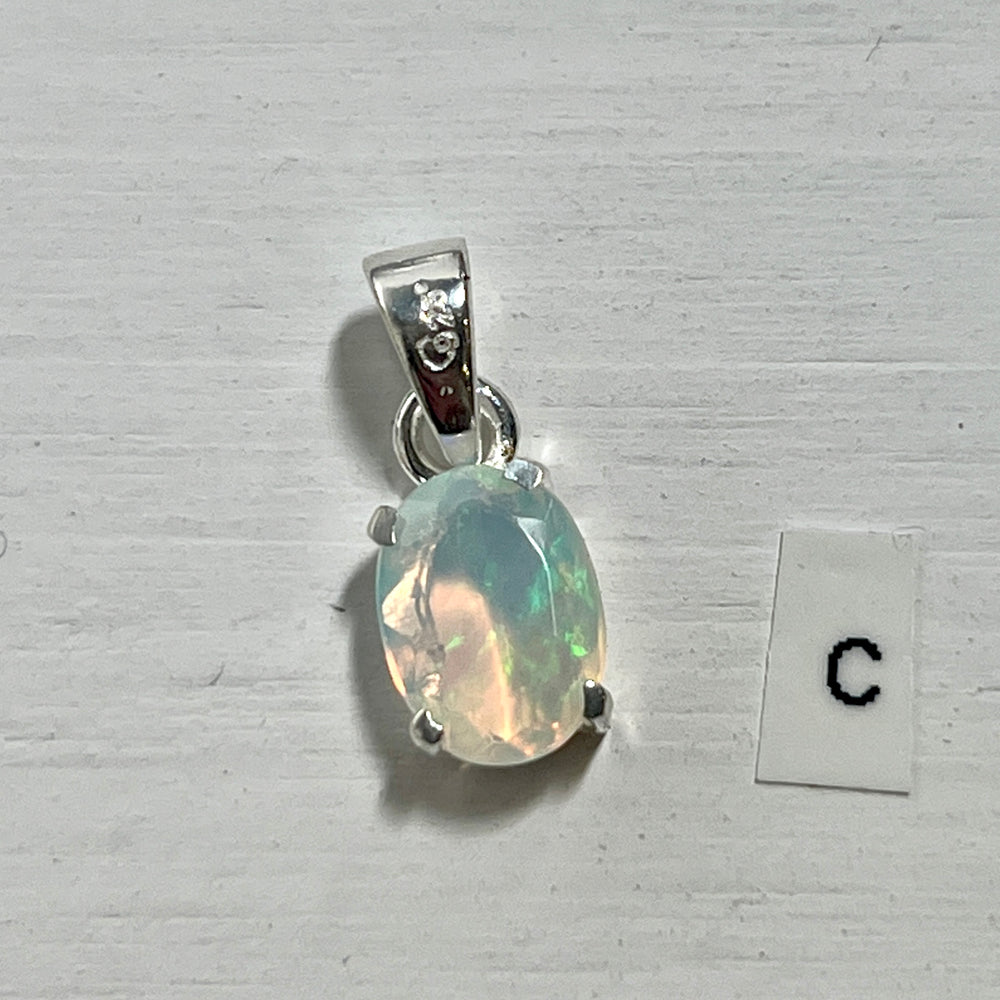 
                  
                    A dainty Super Silver Tiny Facet Cut Prong Set Ethiopian Opal Pendant with the letter c next to it, made of .925 sterling silver.
                  
                