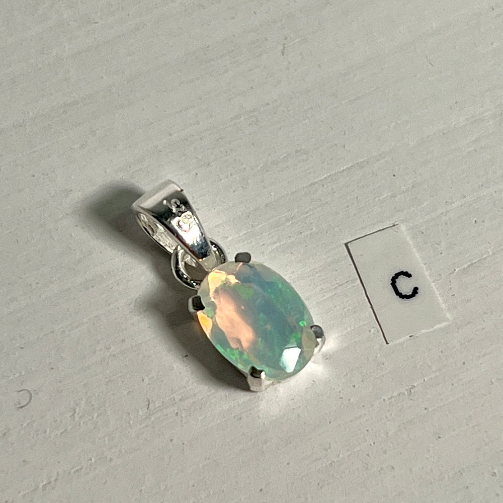 
                  
                    A dainty pendant made by Super Silver, featuring a Tiny Facet Cut Prong Set Ethiopian Opal and the letter c.
                  
                