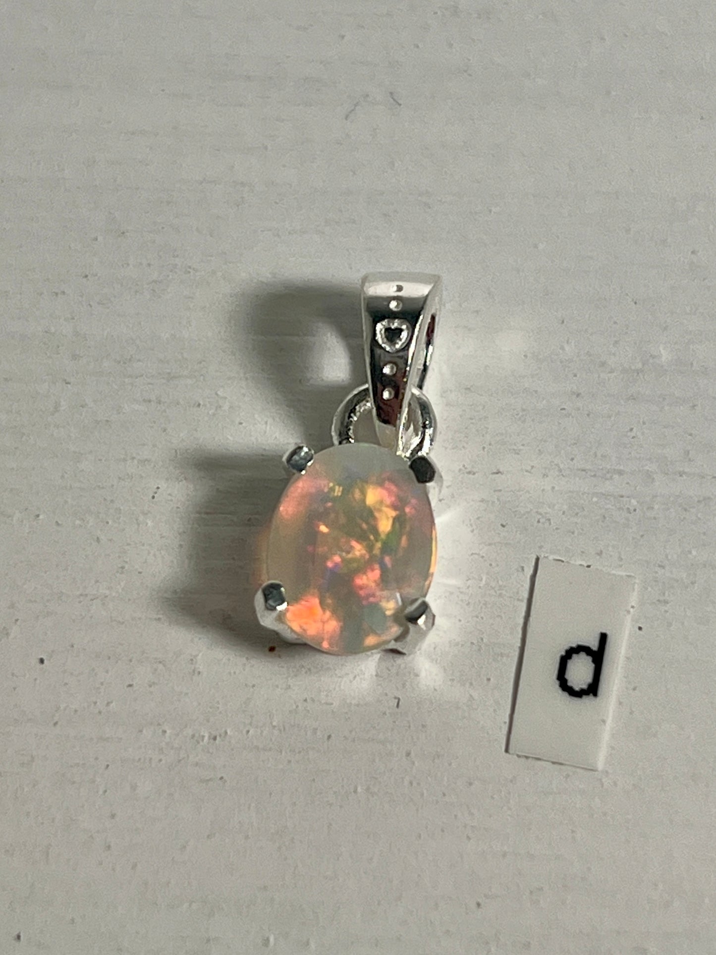 
                  
                    A Tiny Facet Cut Prong Set Ethiopian Opal Pendant in .925 sterling silver with the letter "d" elegantly displayed from Super Silver.
                  
                