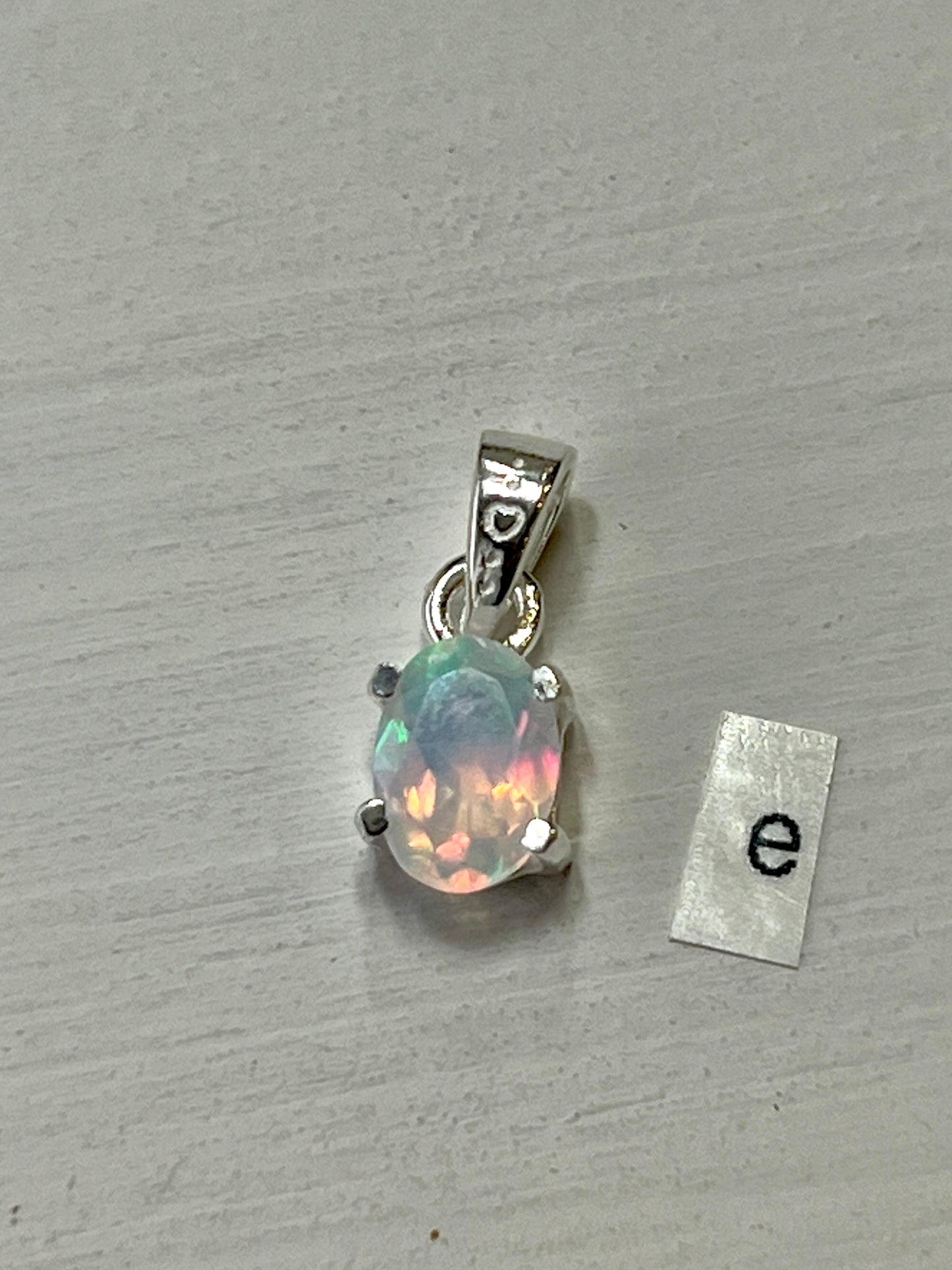 
                  
                    A Tiny Facet Cut Prong Set Ethiopian Opal Pendant featuring an Ethiopian opal and crafted by Super Silver in .925 sterling silver, adorned with the letter e.
                  
                