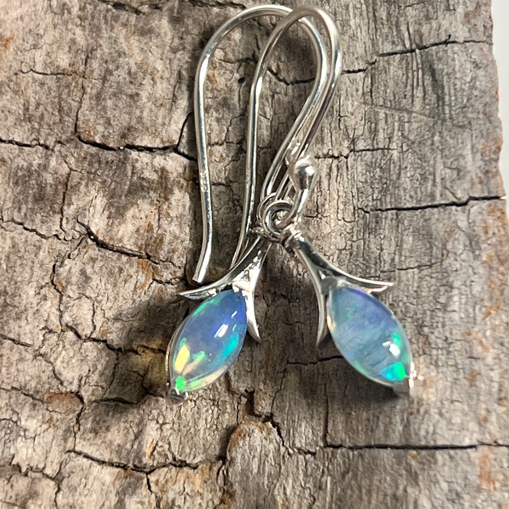 A pair of Modern Marquise Shaped Ethiopian Opal Earrings made with Ethiopian opal pieces, beautifully displayed on a piece of wood, by Super Silver.