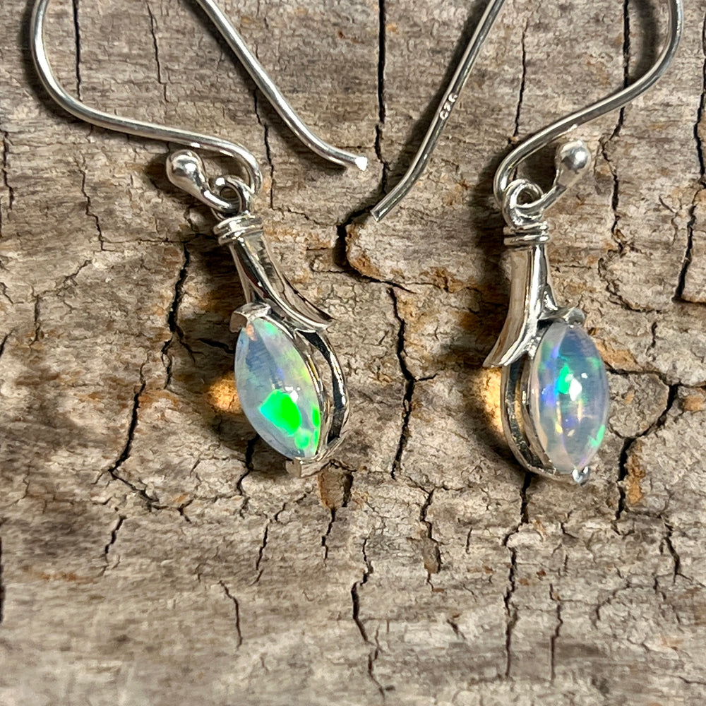 
                  
                    A pair of dainty Modern Marquise Shaped Ethiopian Opal Earrings by Super Silver on a piece of wood.
                  
                