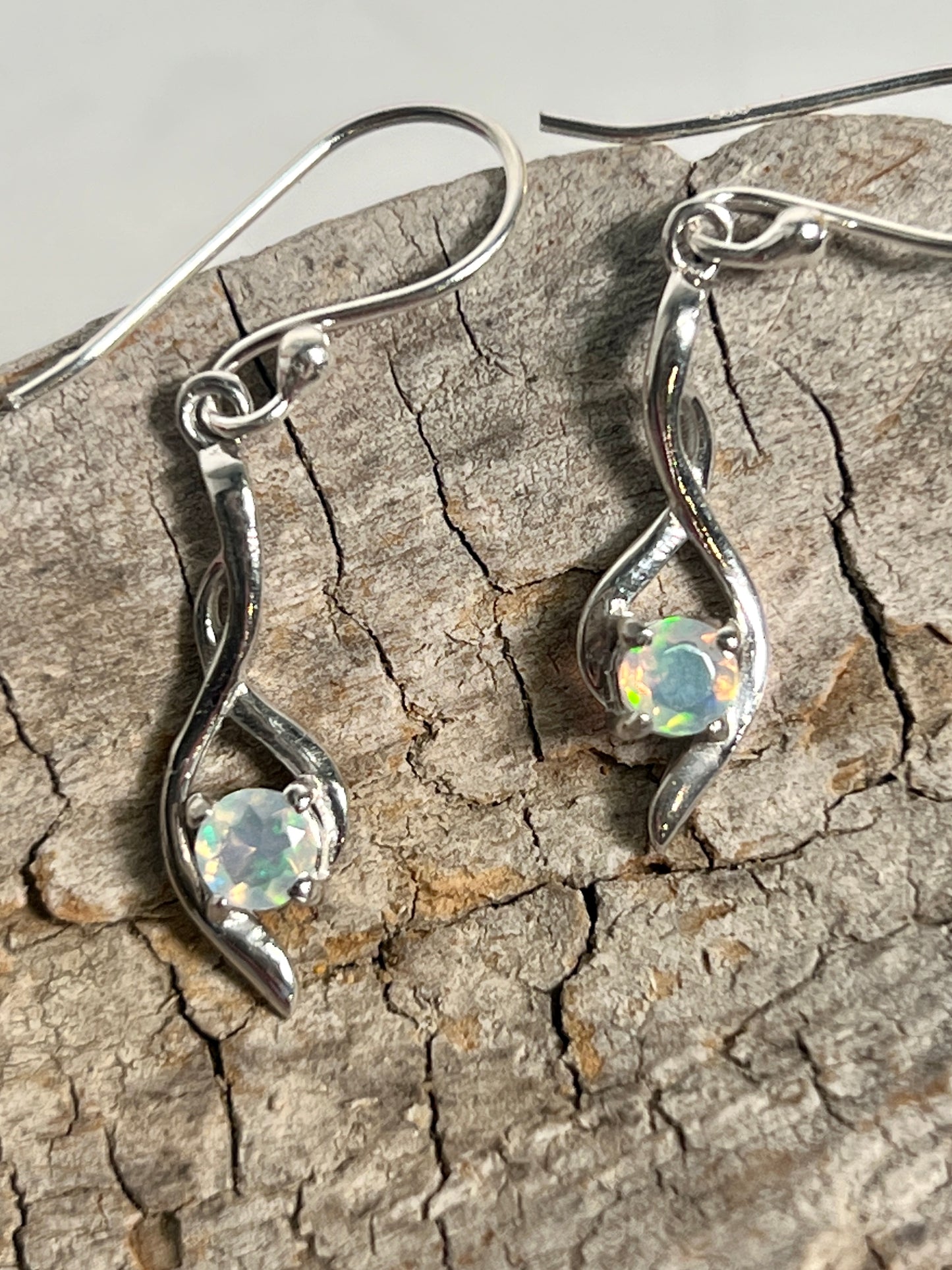
                  
                    A pair of glamorous Modern Ethiopian Opal earrings by Super Silver on a piece of wood.
                  
                