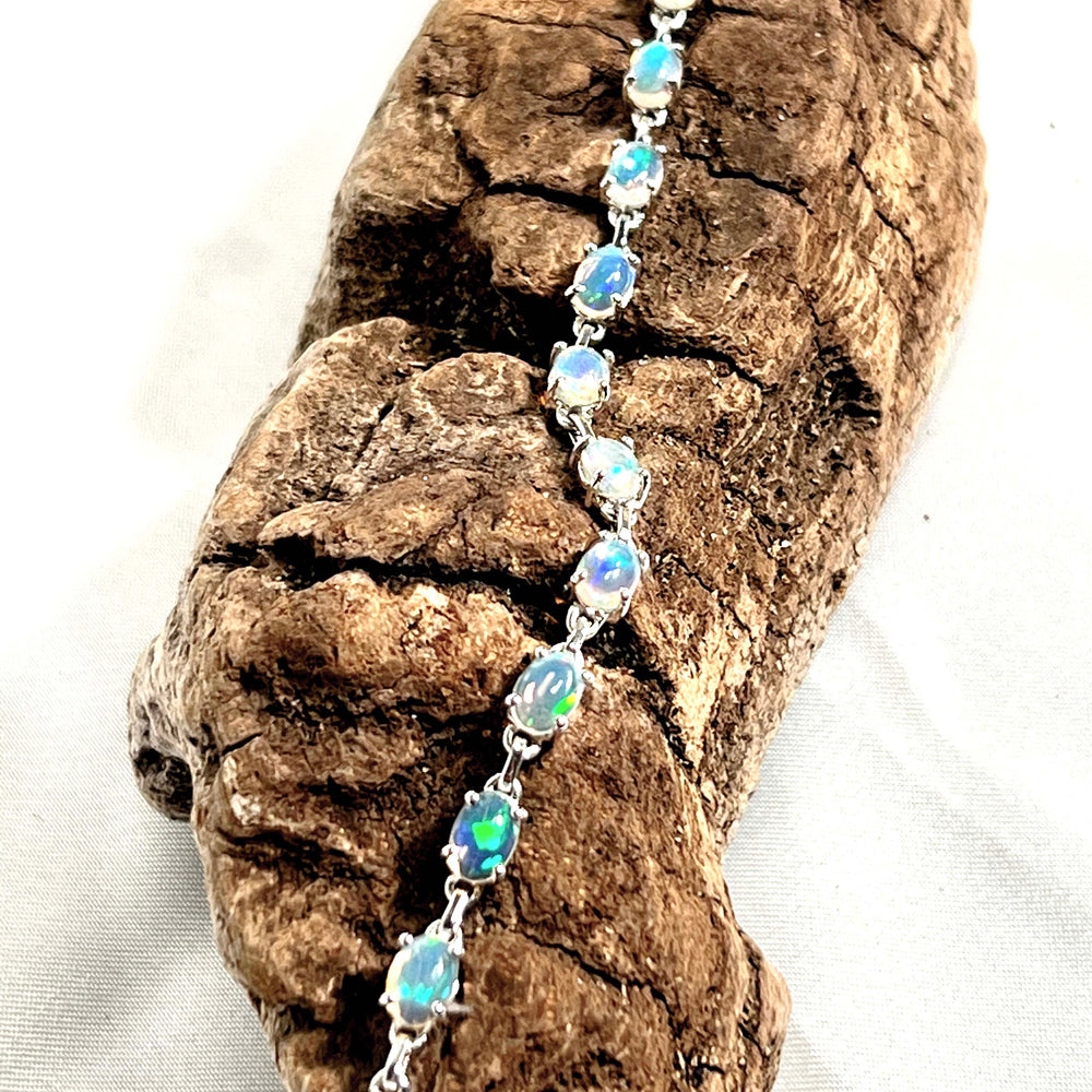 
                  
                    A glamorous Delicate Ethiopian Opal bracelet from Super Silver resting on a rustic piece of wood.
                  
                