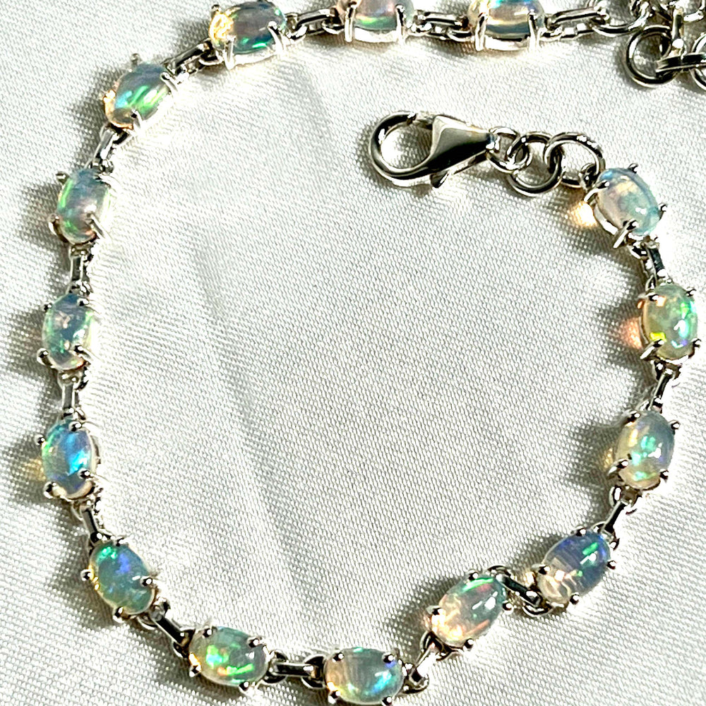 
                  
                    A Super Silver Delicate Ethiopian Opal bracelet exudes glamour as it rests delicately on a pristine white table.
                  
                