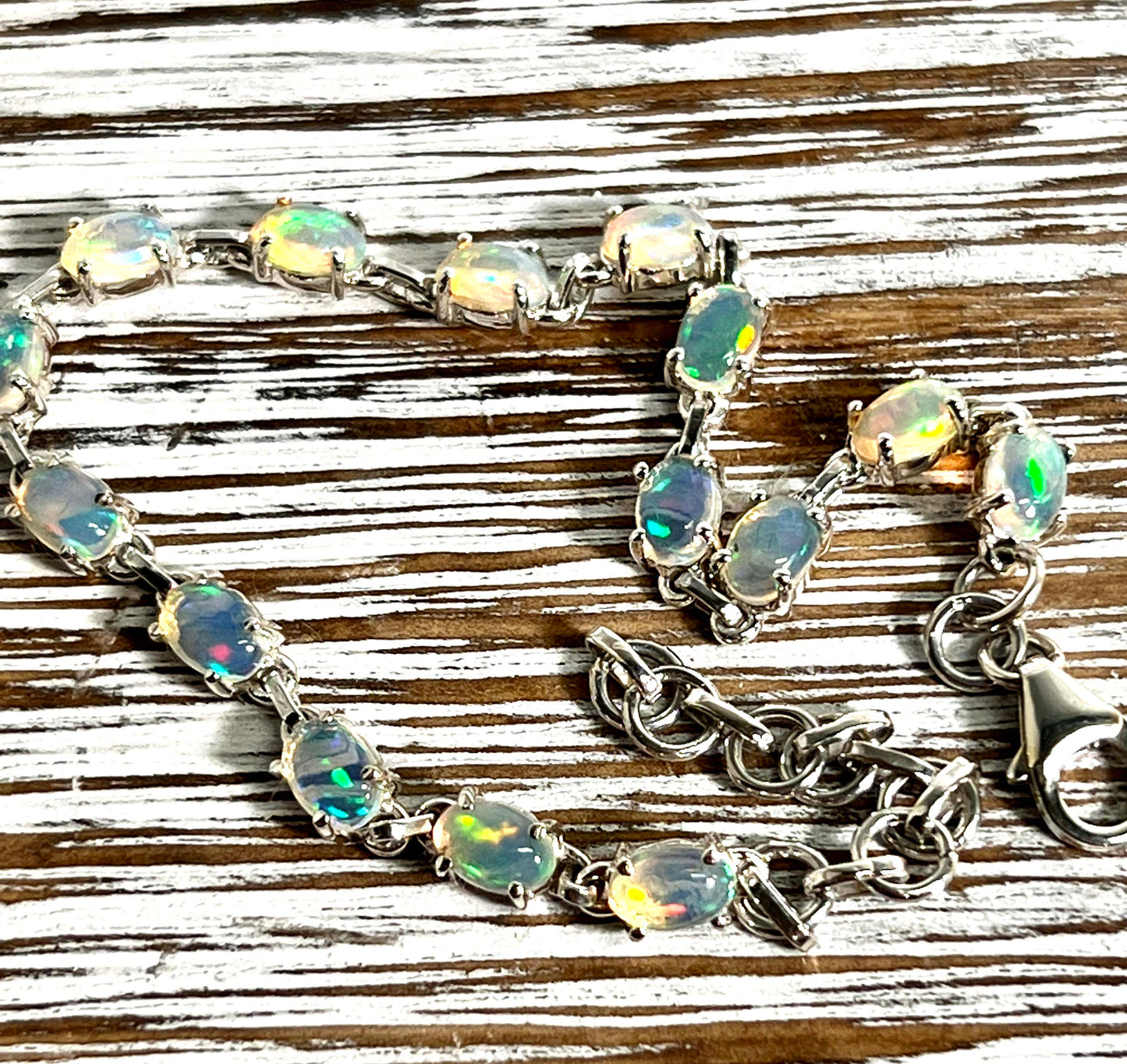 
                  
                    A glamorous Delicate Ethiopian Opal Super Silver bracelet shines brilliantly on a wooden table.
                  
                