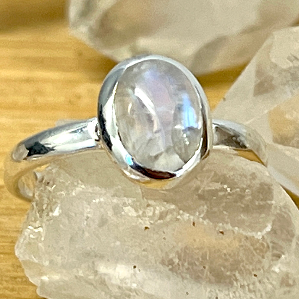 
                  
                    A Simple Oval Moonstone Or Labradorite Ring featuring a moonstone cabochon atop crystals.
                  
                