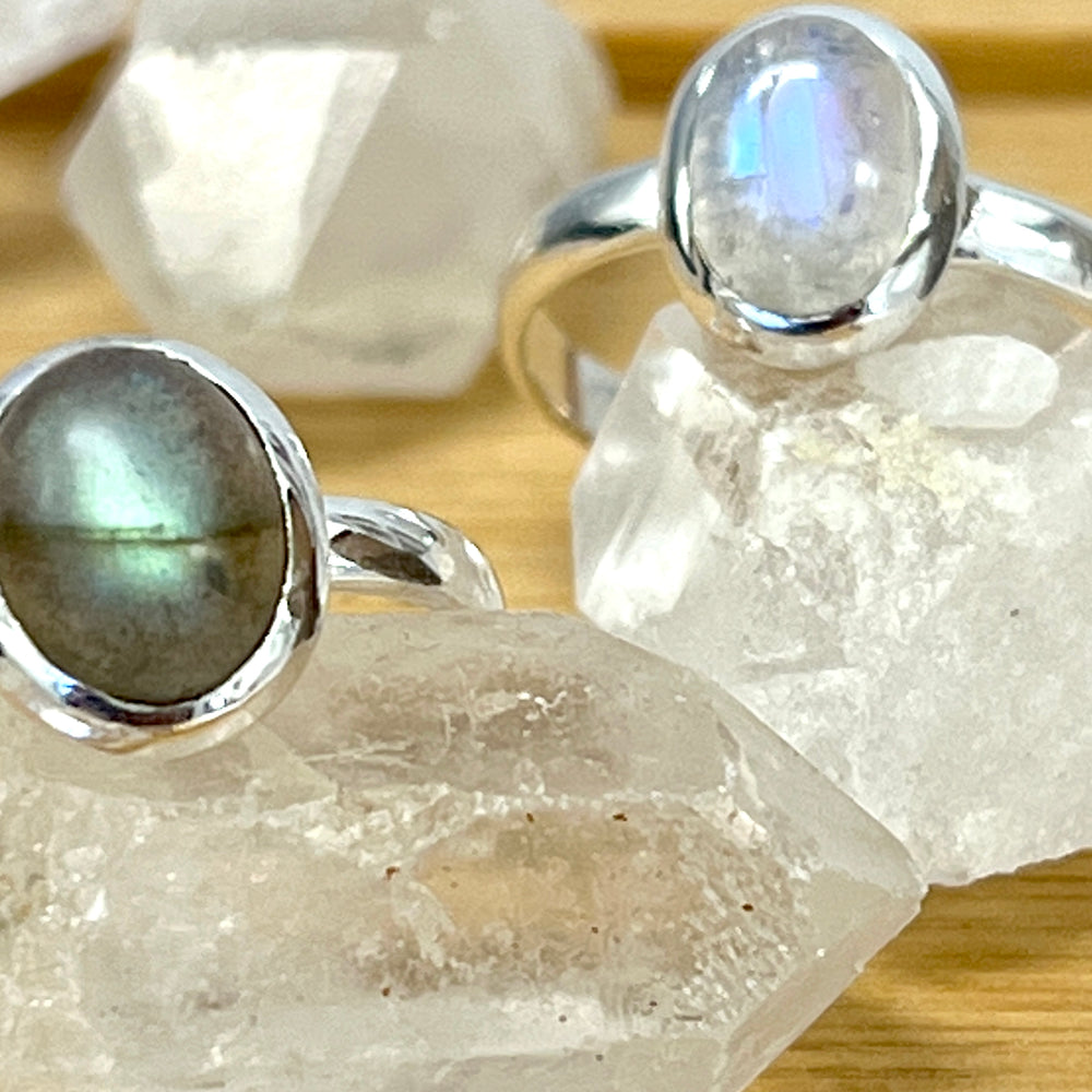 Two sterling silver Simple Oval Moonstone Or Labradorite Rings on top of a table.