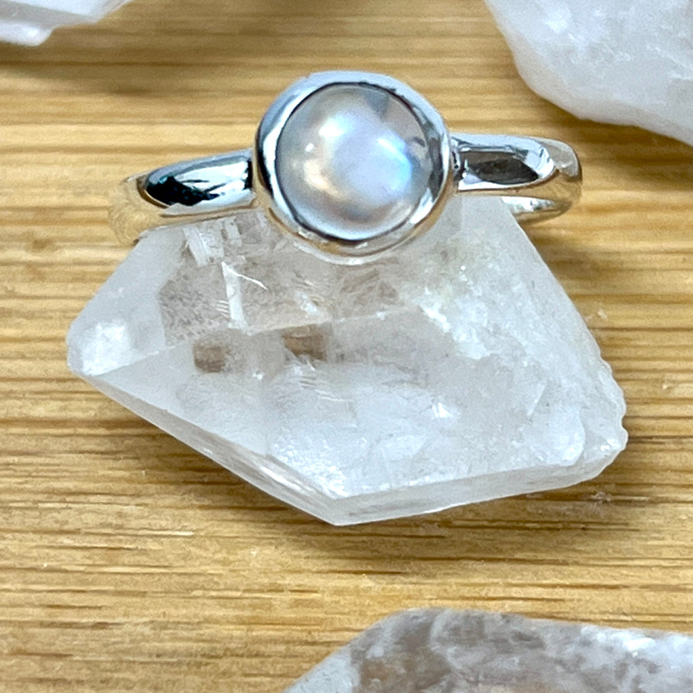 
                  
                    A Super Silver ring adorned with a Simple Moonstone and Labradorite Stacking Ring on top of crystals.
                  
                