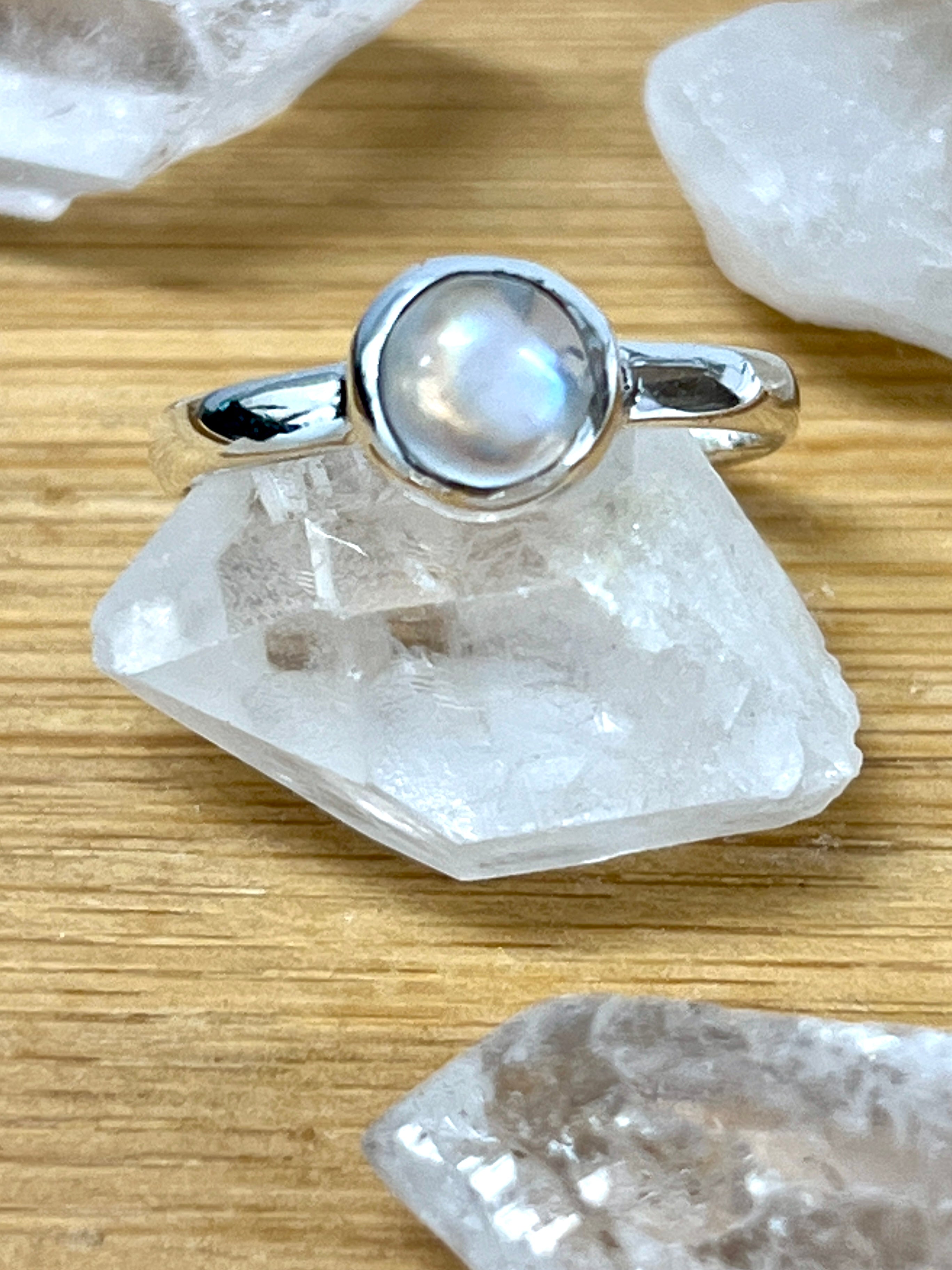 A Super Silver ring adorned with a Simple Moonstone and Labradorite Stacking Ring on top of crystals.