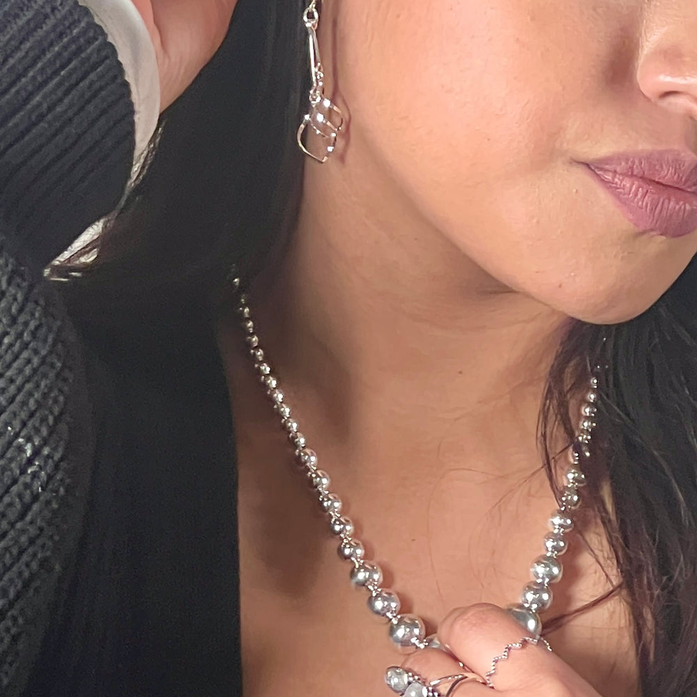 
                  
                    A woman wearing Super Silver's Delicate Twisted Freeform Earrings and a necklace.
                  
                