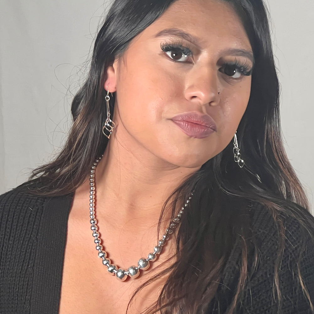 
                  
                    A woman wearing a black cardigan and necklace accessorized with Super Silver's Delicate Twisted Freeform Earrings.
                  
                
