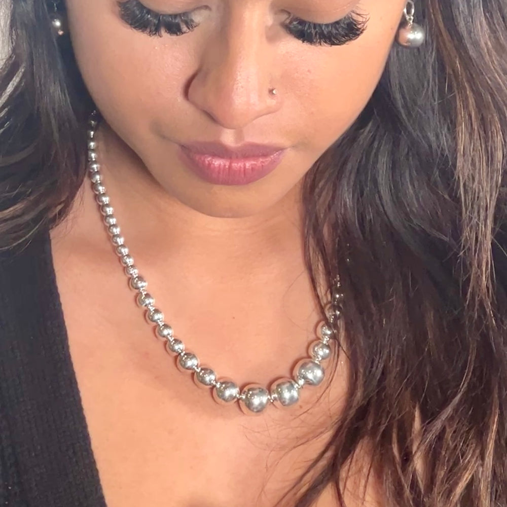 A woman wearing a Super Silver Graduated Silver Bead Necklace and a silver beaded ring.