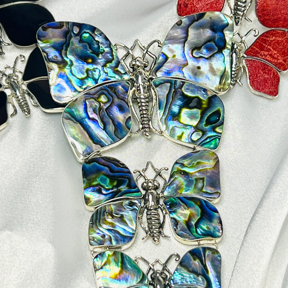 
                  
                    A group of Super Silver statement pendants/brooches with three butterflies on a white cloth, perfect for any nature lover looking to make a statement.
                  
                