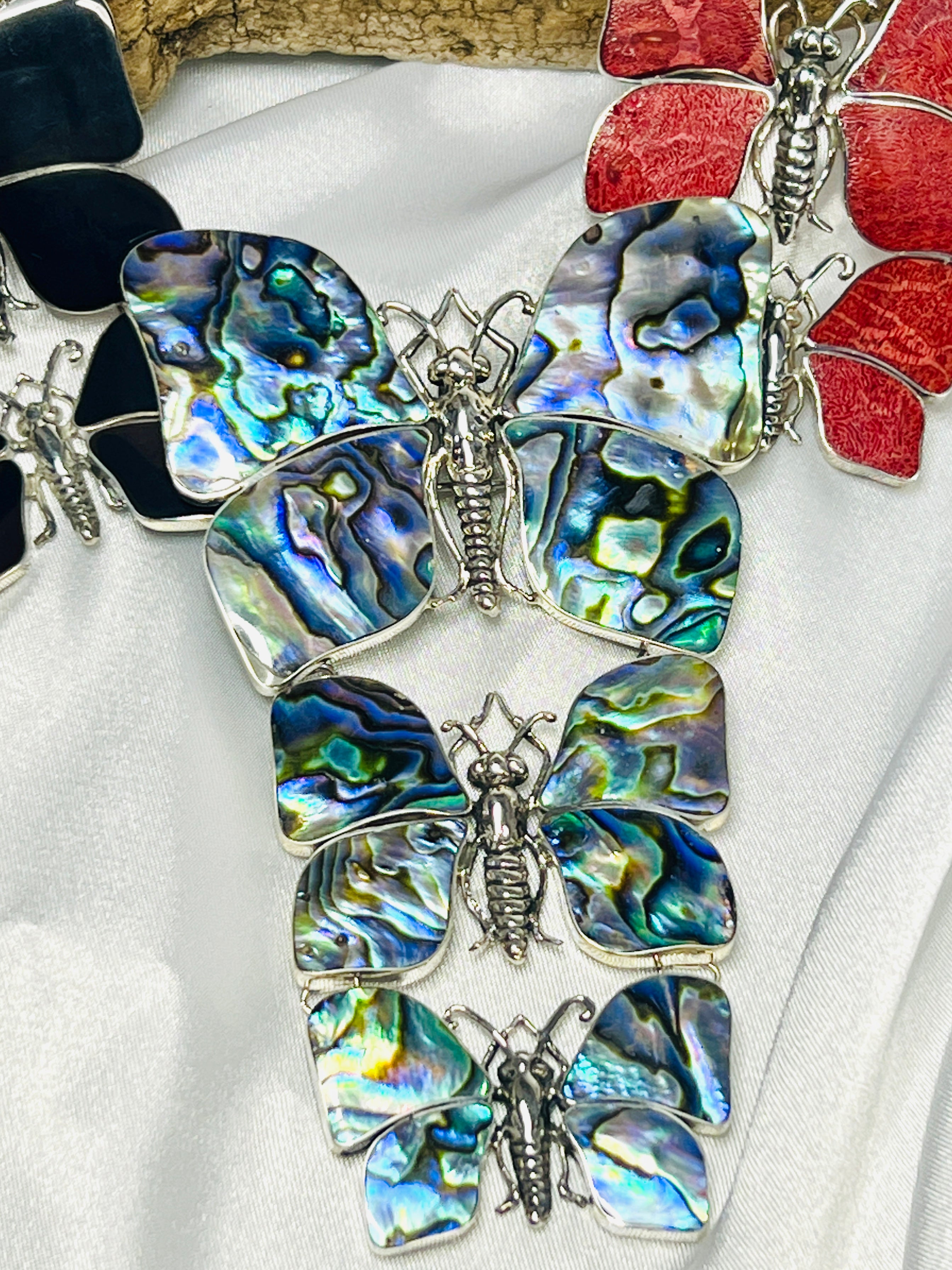 Close-up of intricately designed Statement Pendant or Brooch with Three Butterflies made from iridescent abalone shell and Sterling Silver, arranged on a white surface—an ideal treasure for any nature lover.