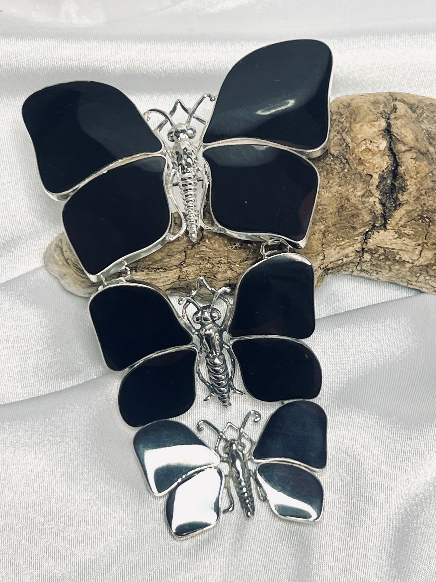 
                  
                    Three stunning Super Silver black butterfly pendants delicately arranged on a piece of wood, creating a captivating statement for any nature lover.
                  
                