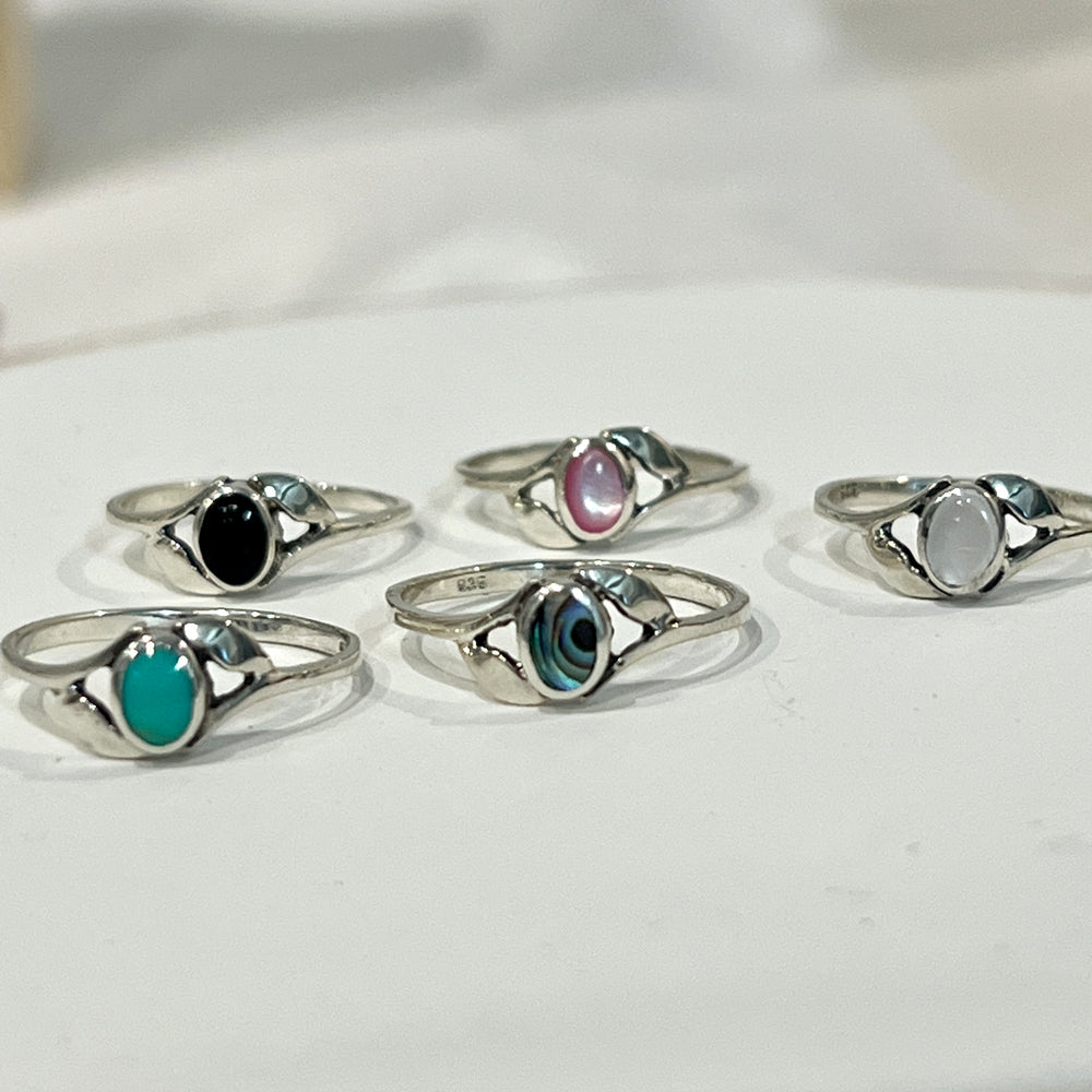 A set of Super Silver Dainty Oval Stone Rings with Leaf Accents, including mother of pearl, on top of a plate.