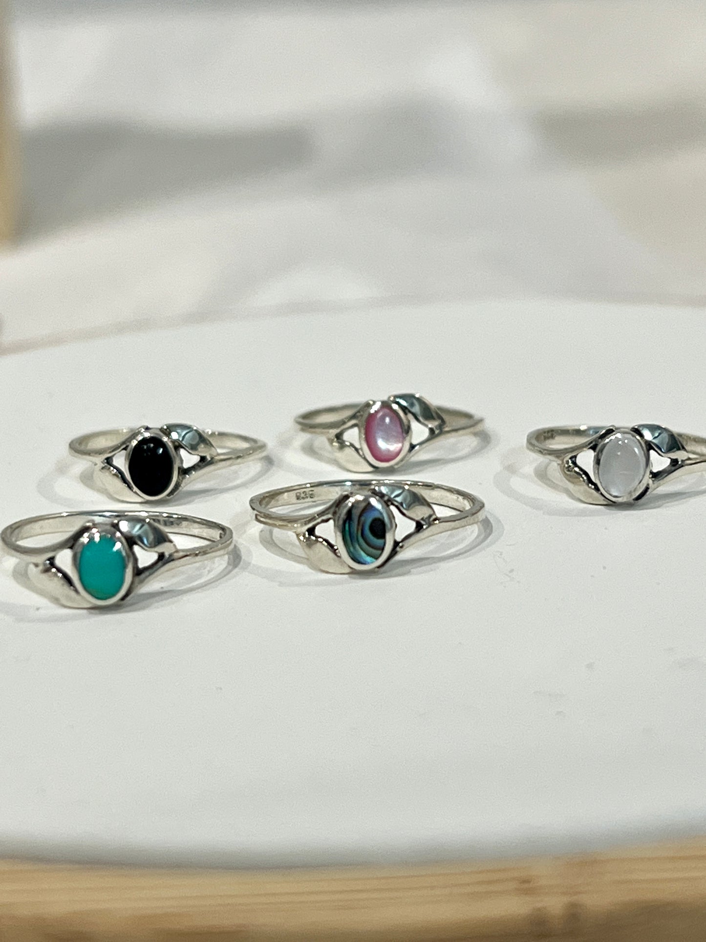 A set of Super Silver Dainty Oval Stone Rings with Leaf Accents, including mother of pearl, on top of a plate.