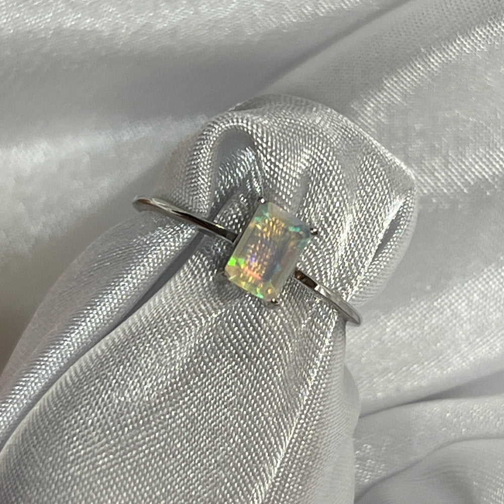 A cushion cut Ethiopian opal ring sitting on a white cloth.