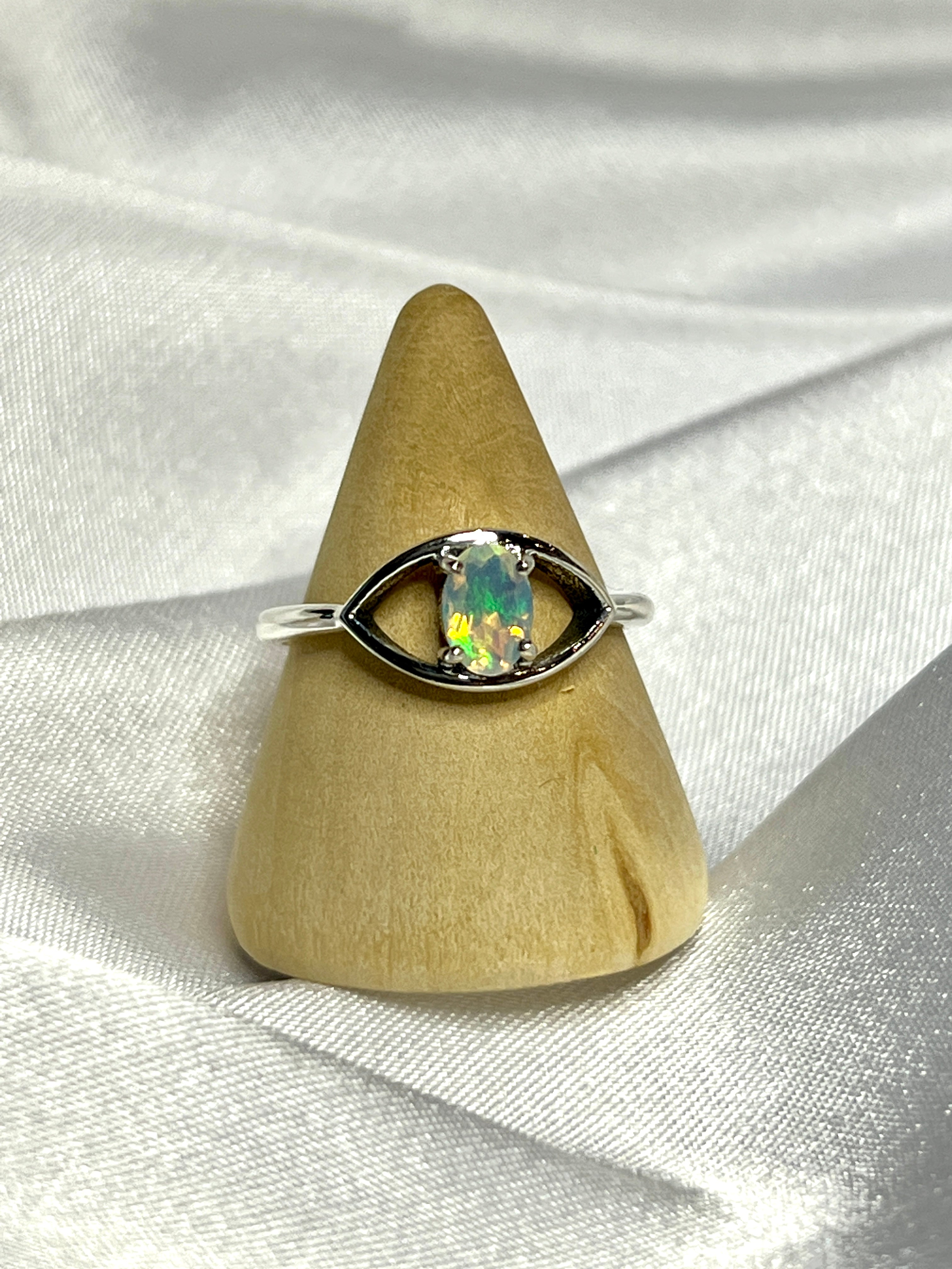 An elegant Facet Cut Ethiopian Opal Evil Eye Ring on a white background.