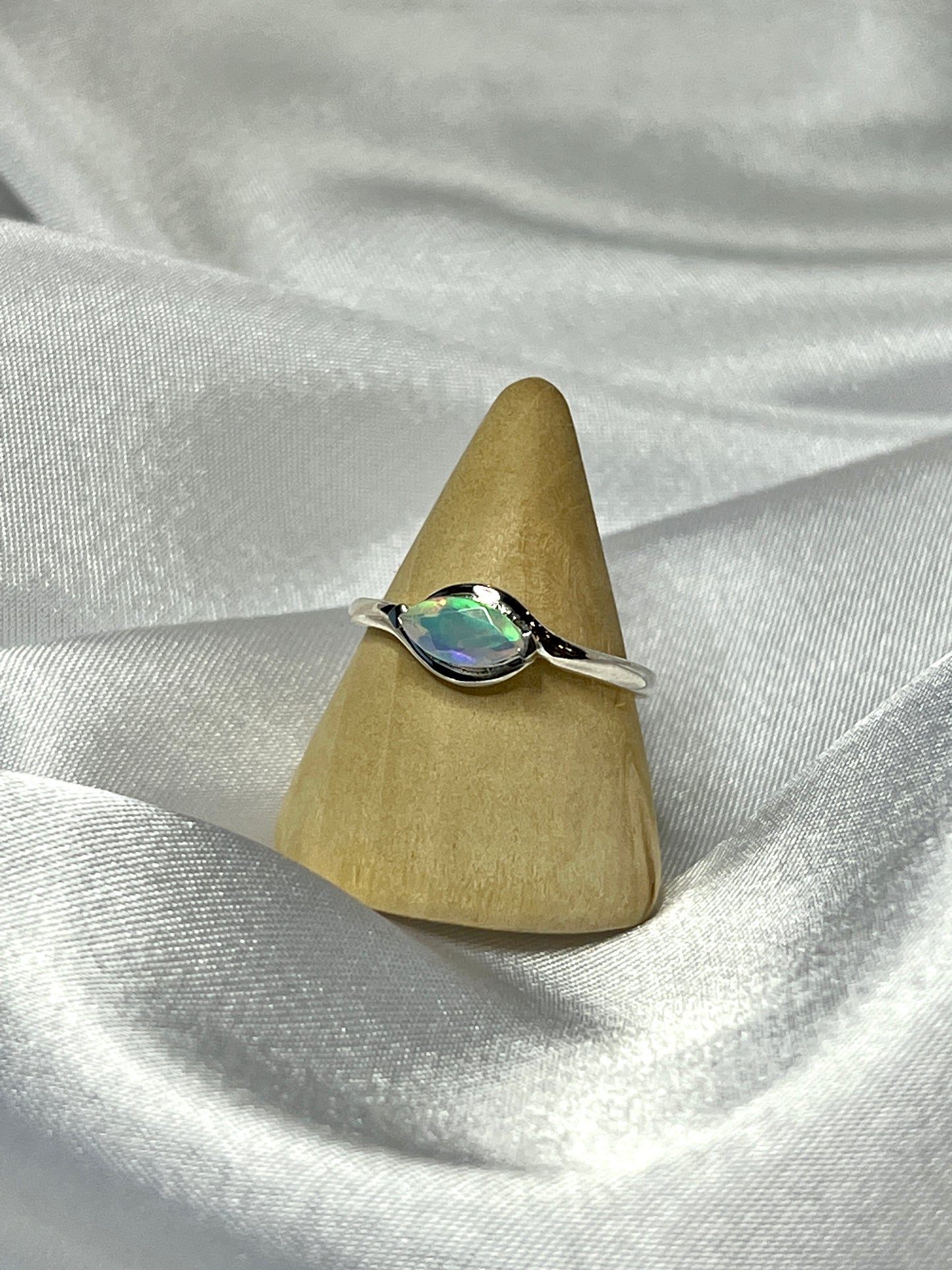 
                  
                    A Brilliant Facet Cut Ethiopian Opal ring elegantly showcased on a pristine white cloth.
                  
                