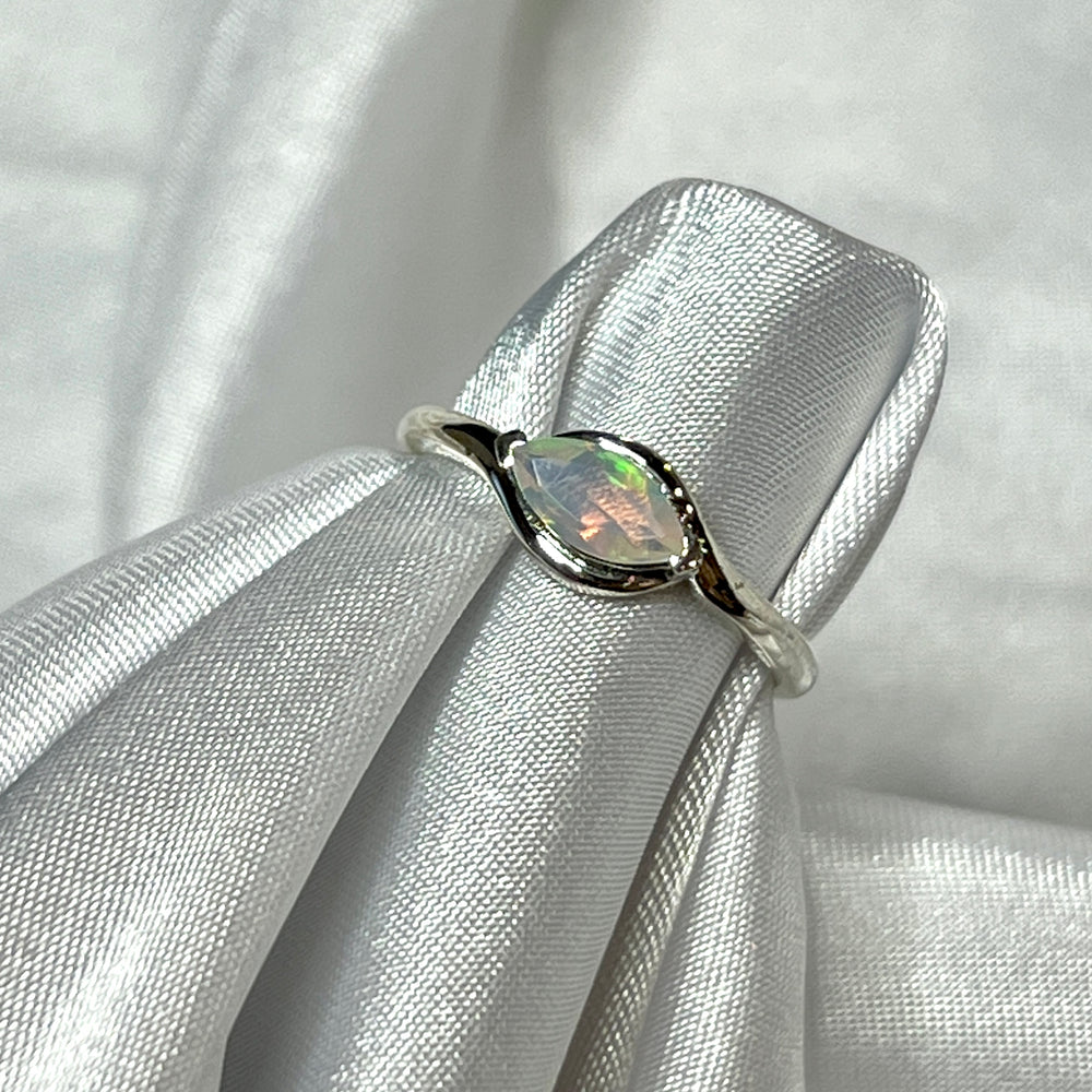
                  
                    A Brilliant Facet Cut Ethiopian Opal ring making a statement as it rests gracefully on a pristine white cloth.
                  
                