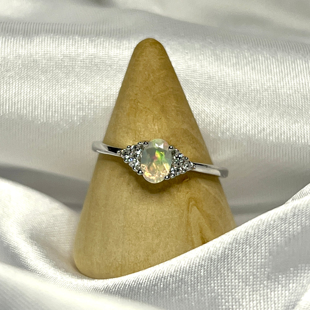 
                  
                    An Ethiopian opal ring with cubic zirconia stones on a white cloth.
                  
                